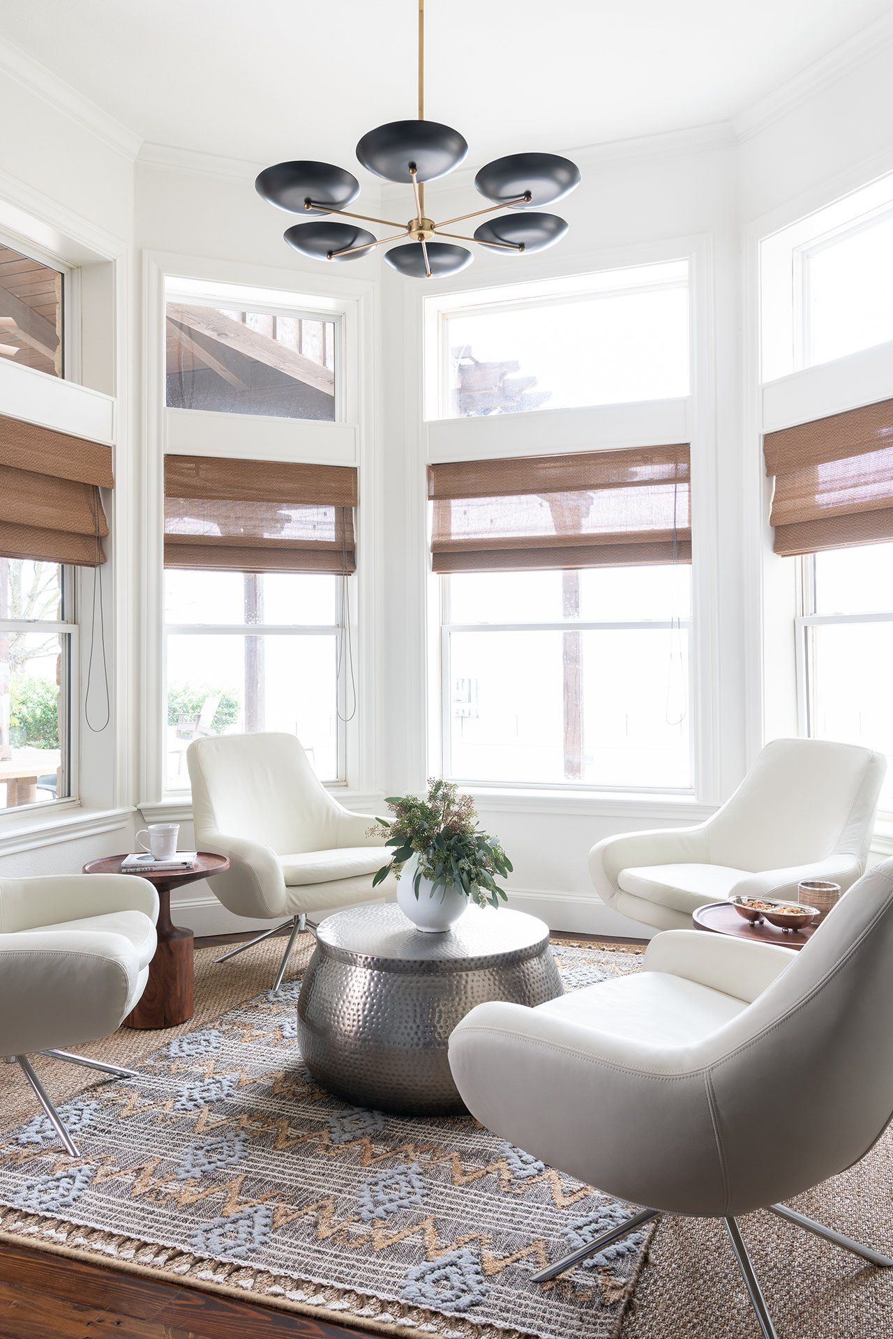 A living room with white chairs , a coffee table , and a chandelier.