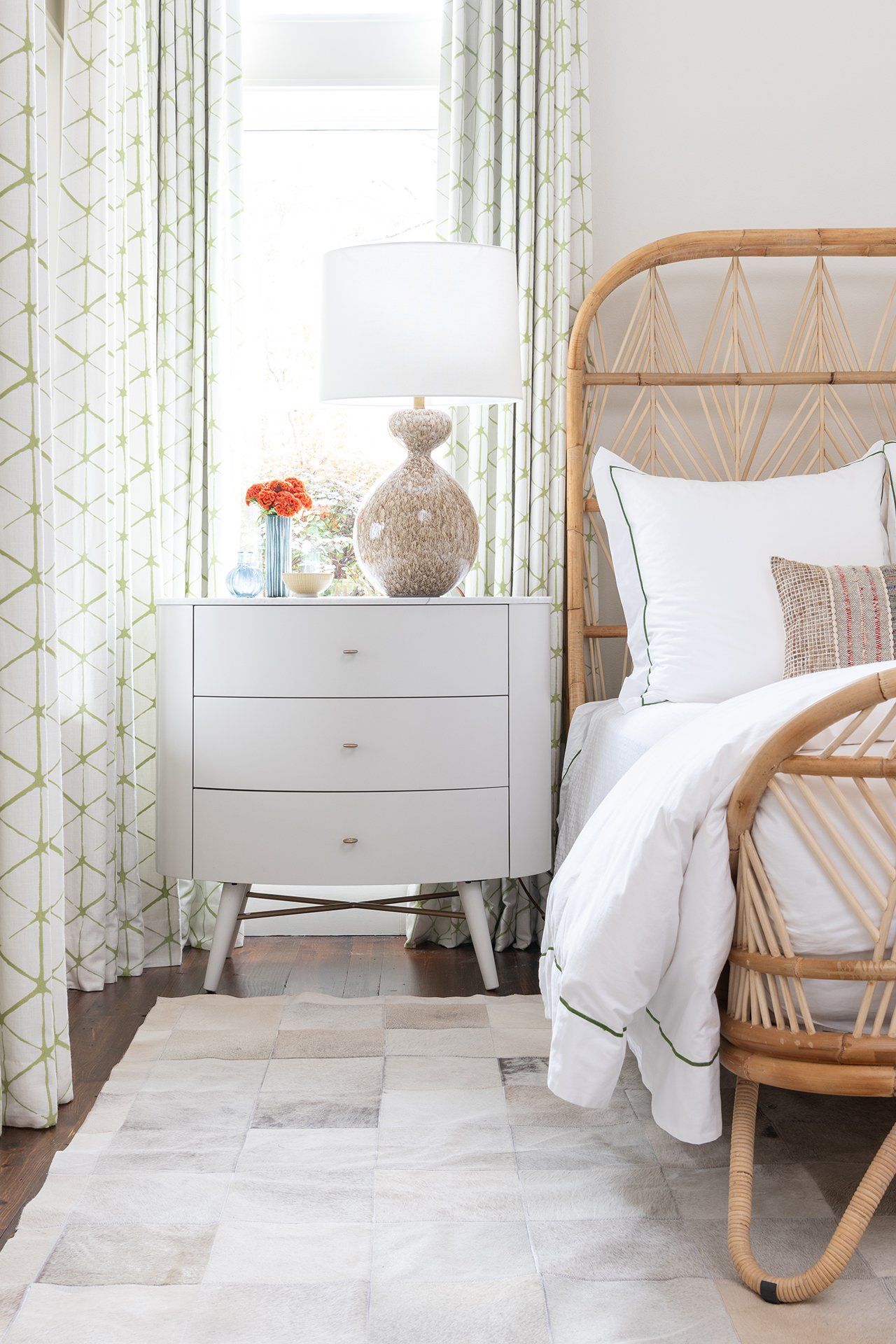 A bedroom with a bed , nightstand , dresser and rug.