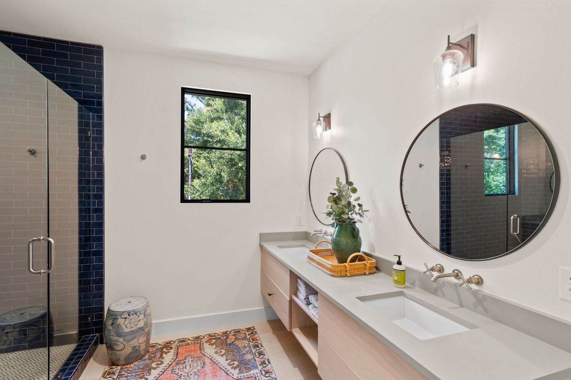 A bathroom with two sinks , a shower and two mirrors.