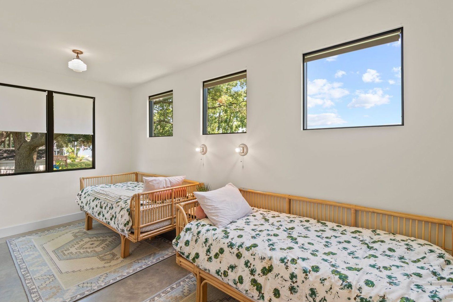 A bedroom with two beds and three windows.