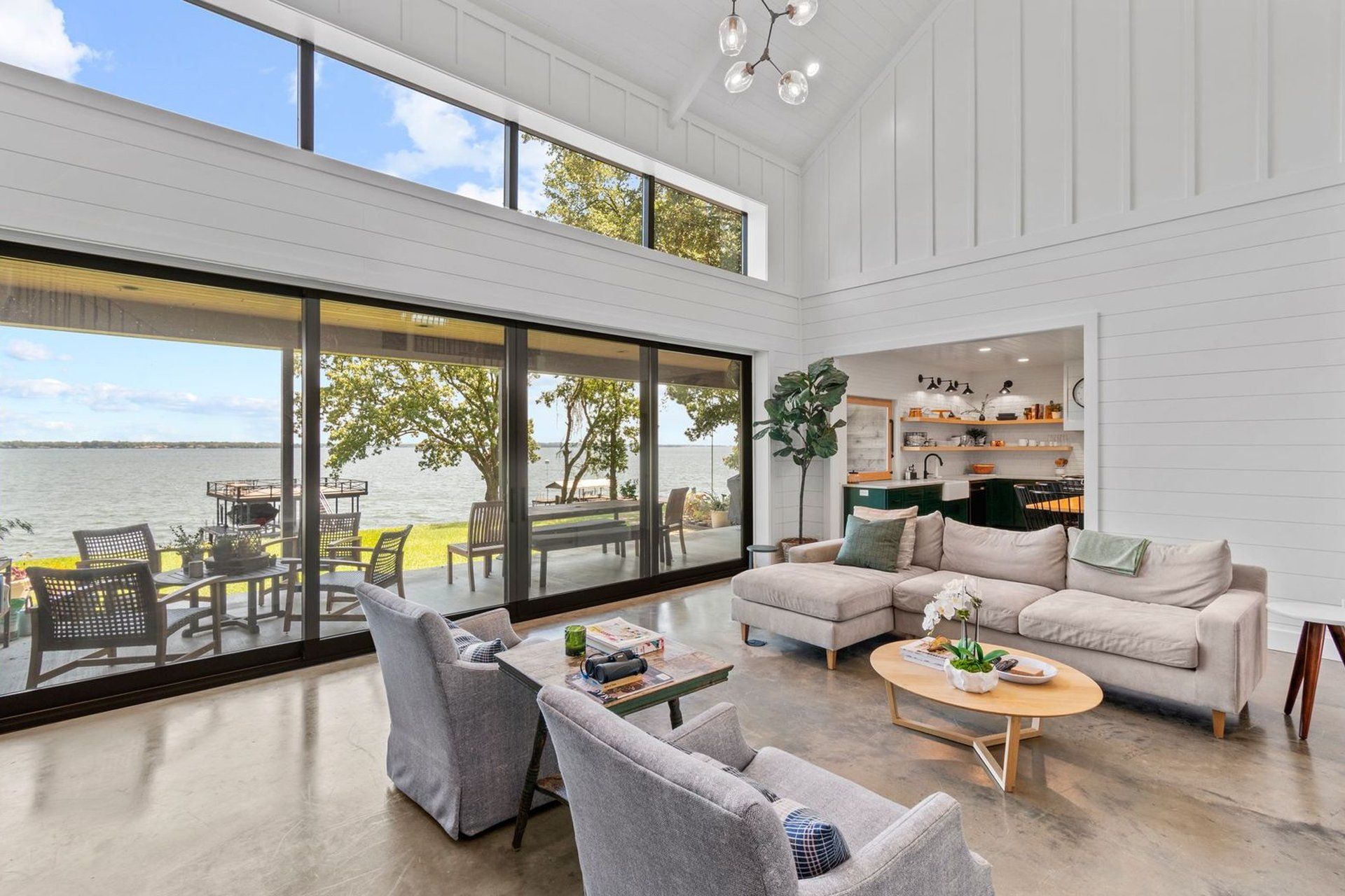 A living room with a couch , chairs , and a table with a view of the water.