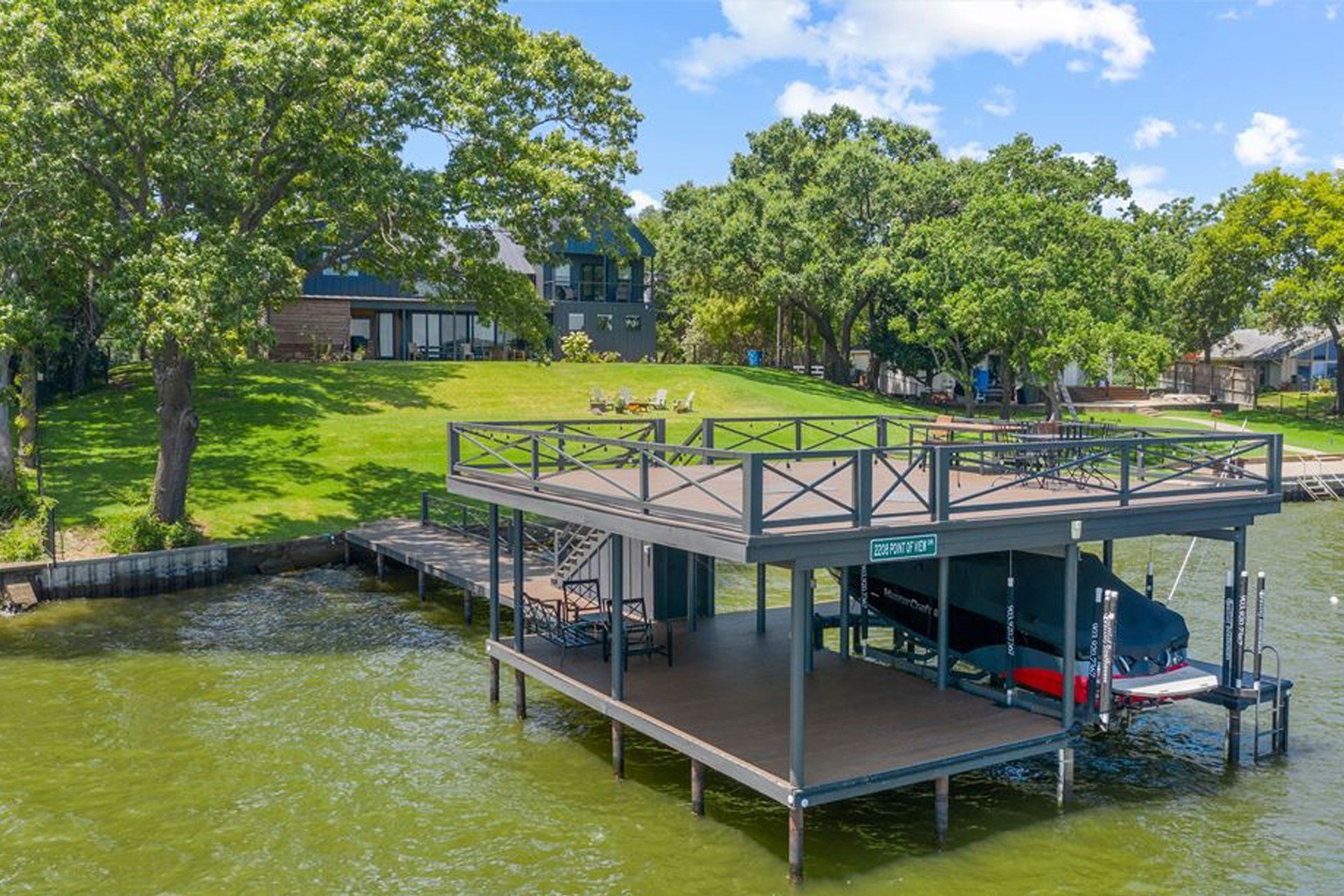 An aerial view of a boat dock on a lake with a house in the background.