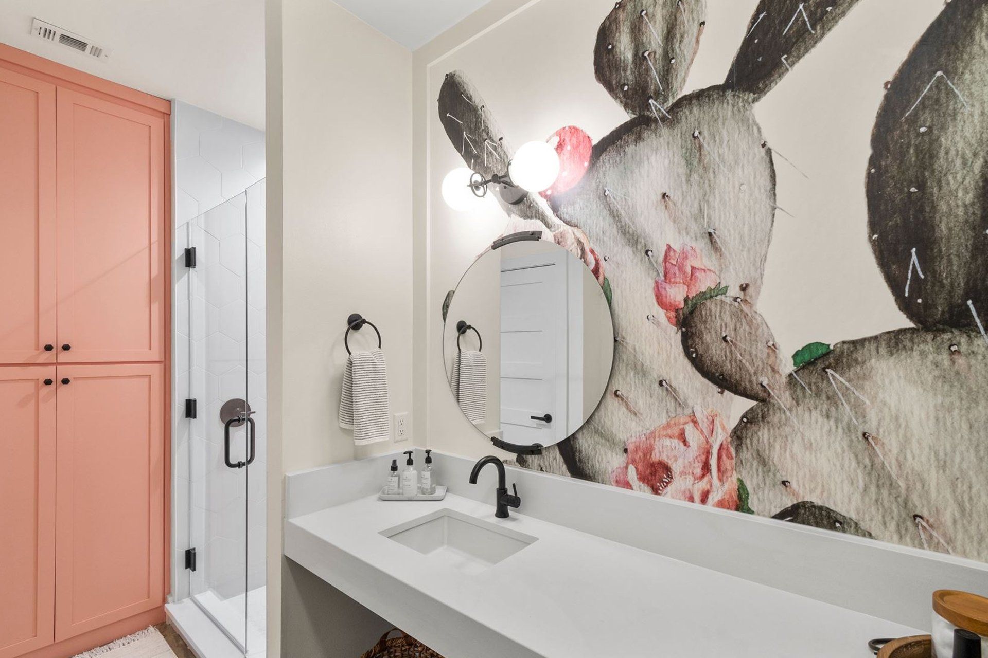 A bathroom with a cactus wallpaper on the wall and a sink.