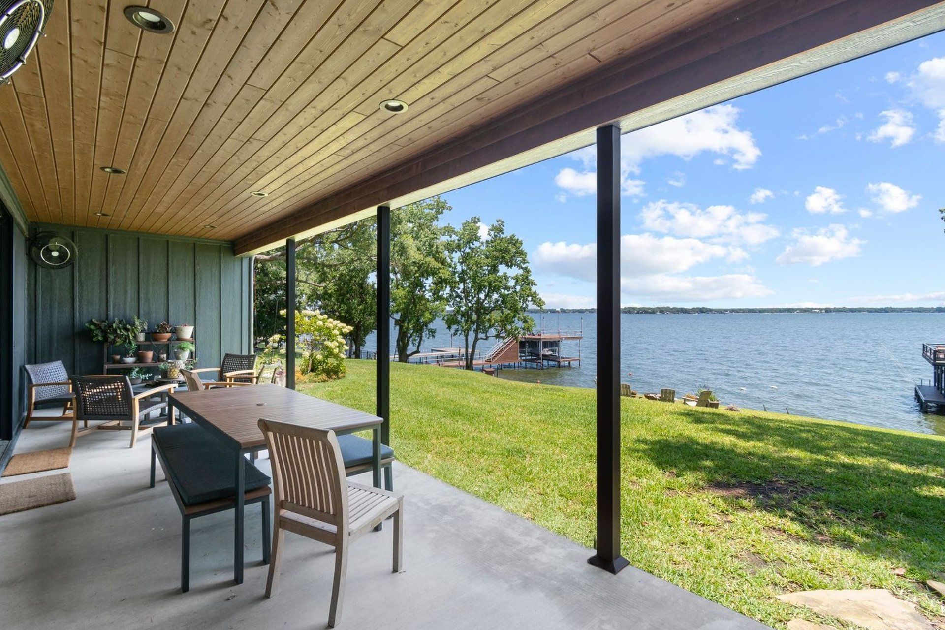A patio with a table and chairs overlooking a lake.