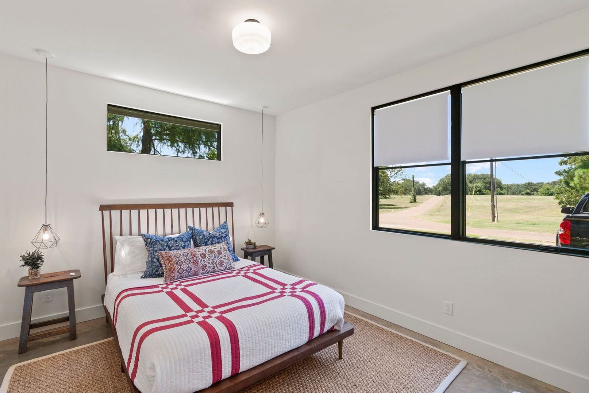 A bedroom with a bed , two windows and a rug.