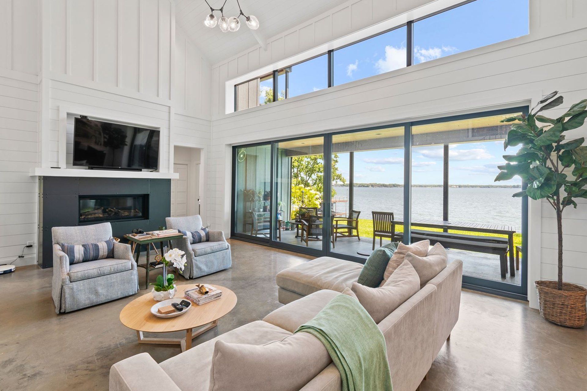 A living room with a couch , chairs , coffee table and television.