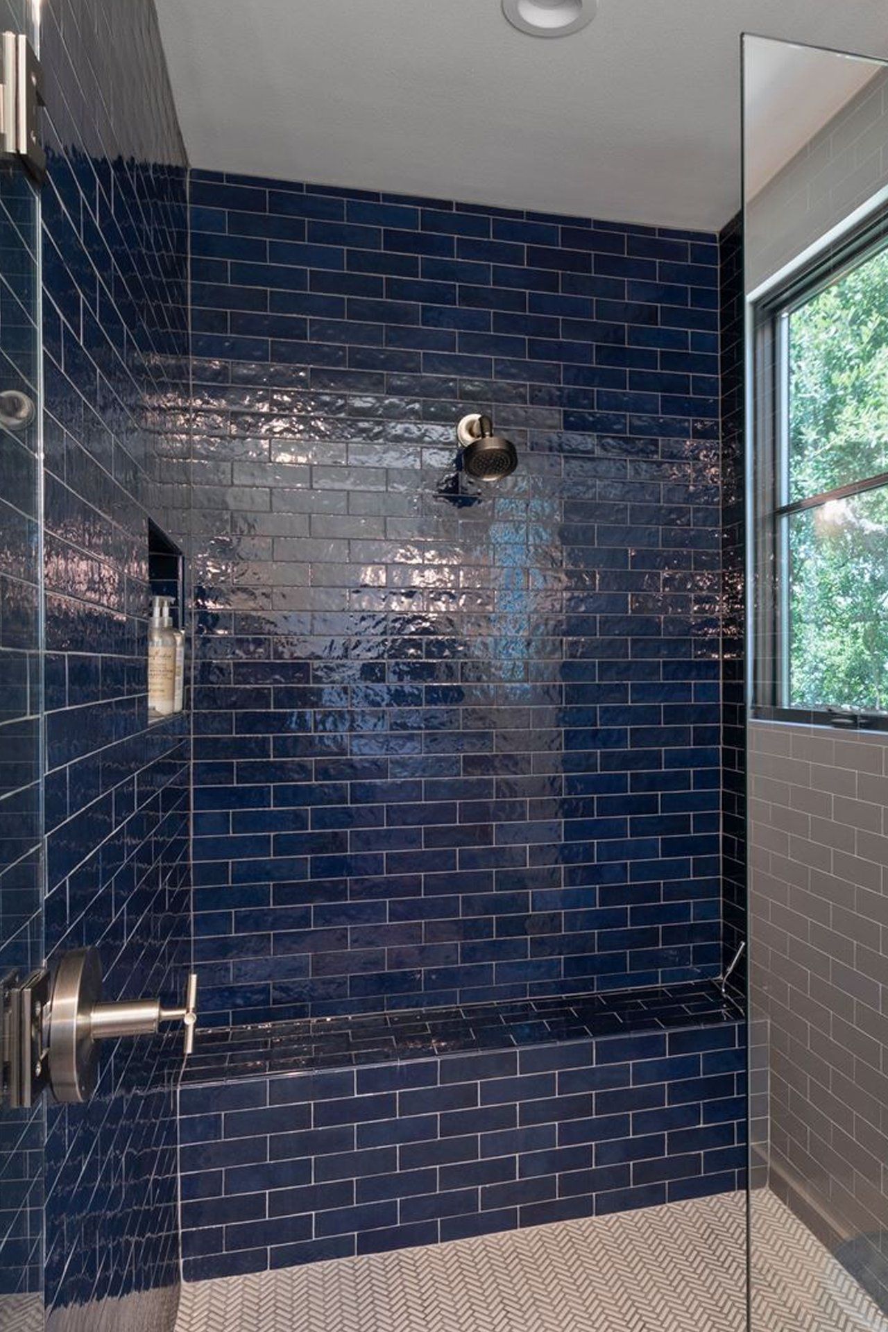 A bathroom with blue brick tiles and a walk in shower.