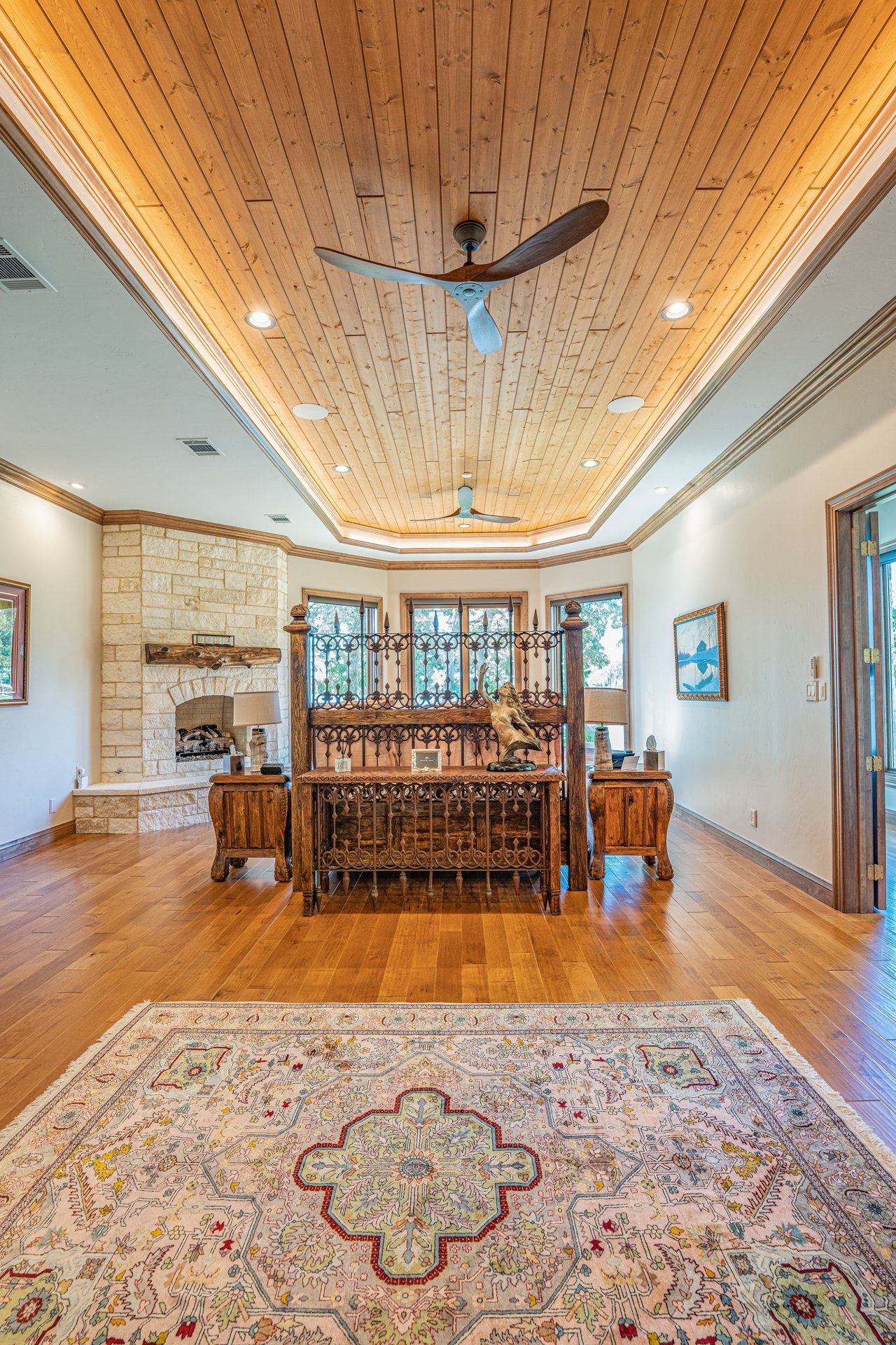 A living room with hardwood floors , a rug , a fireplace and a ceiling fan.