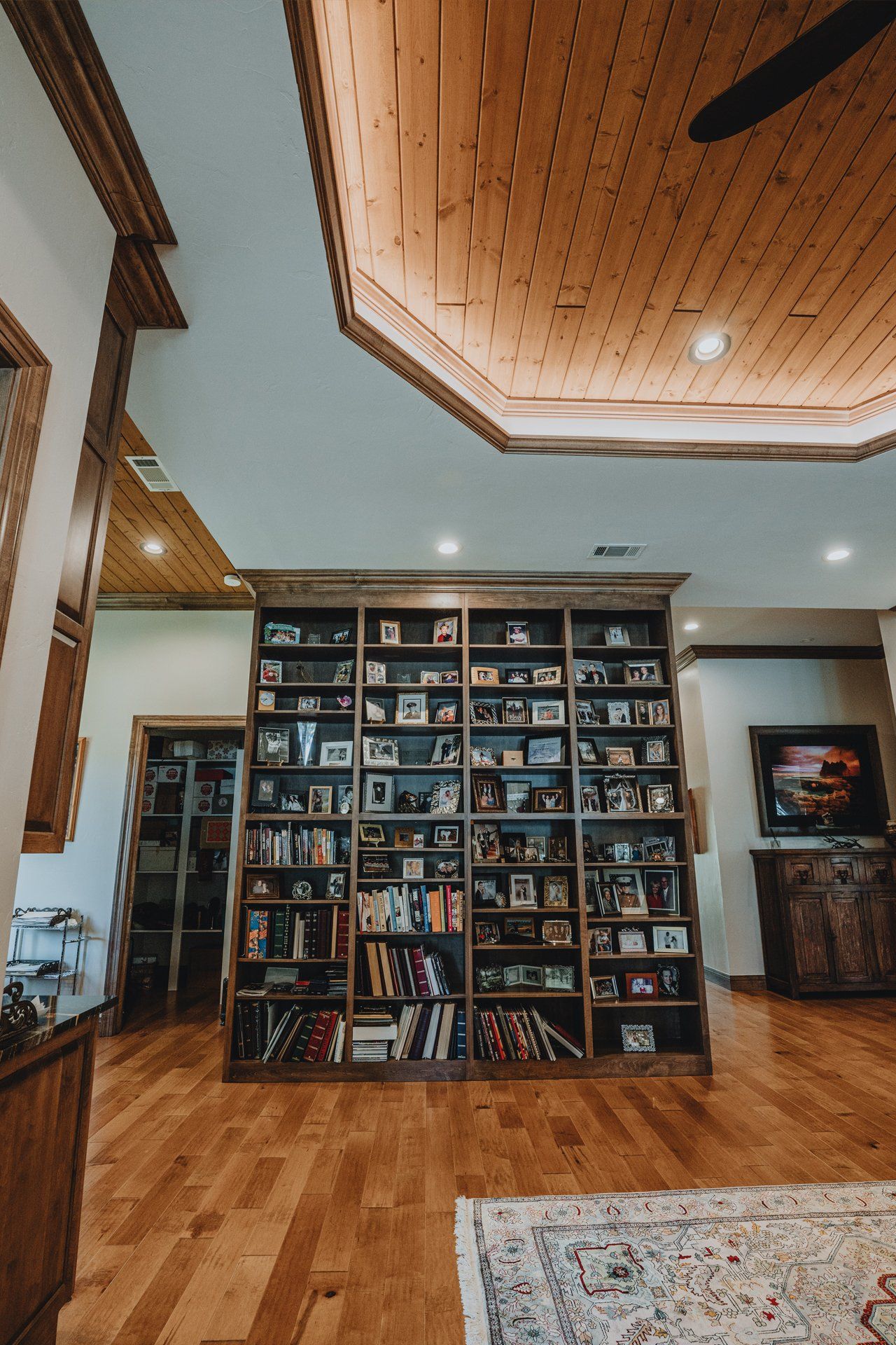 A large bookshelf filled with books and pictures in a living room.