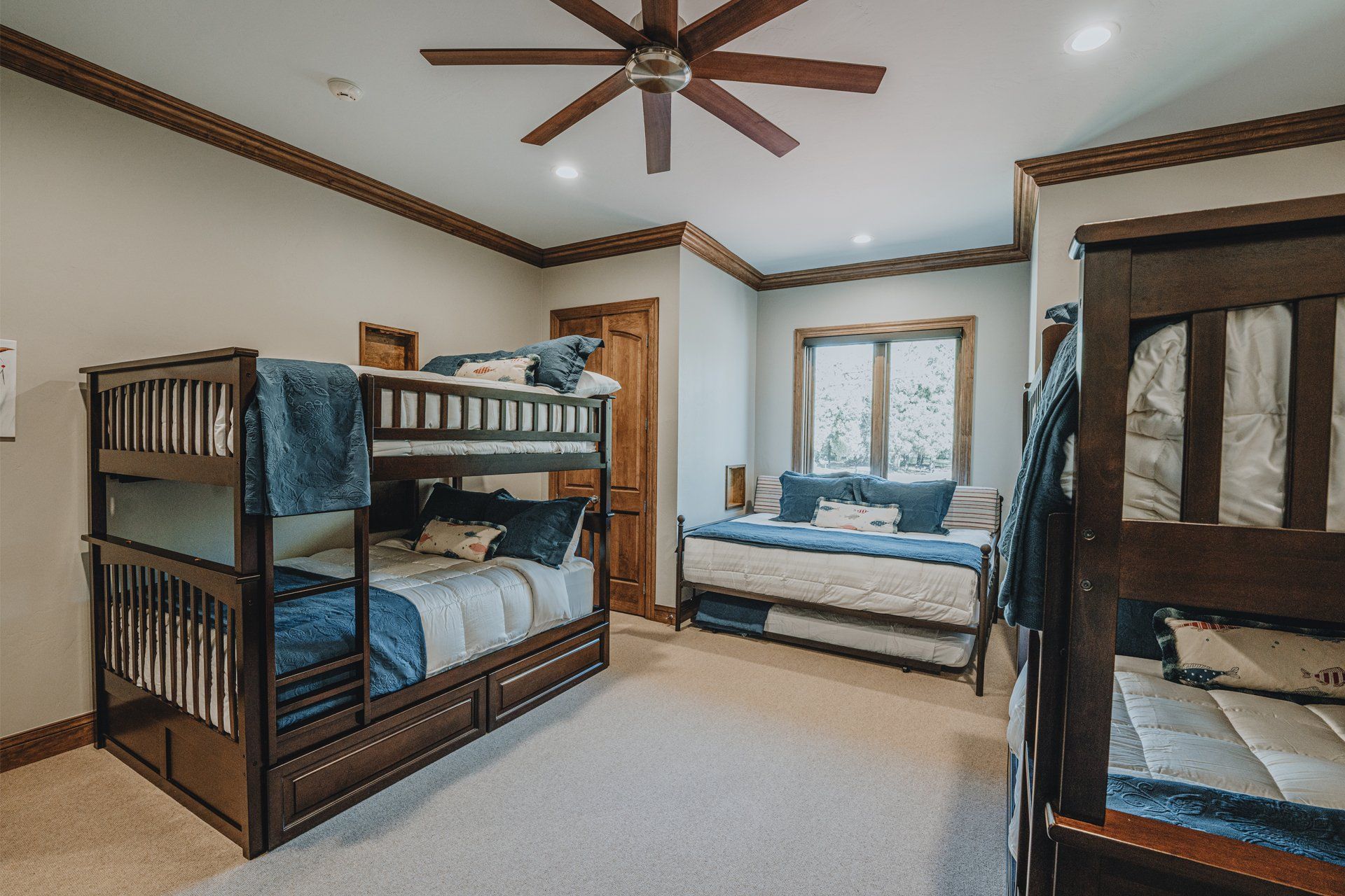A bedroom with bunk beds , a futon , and a ceiling fan.