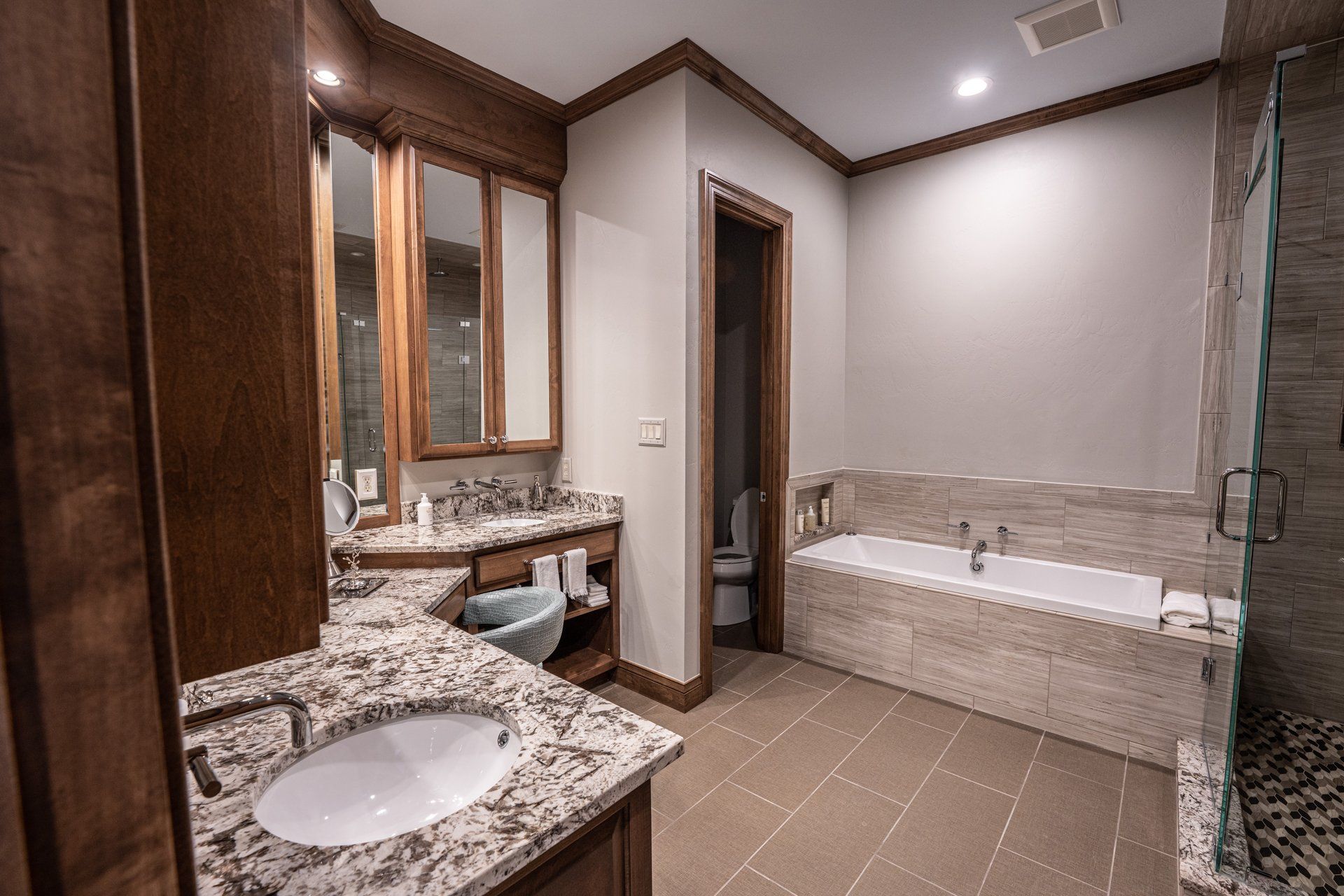 A bathroom with a sink , tub , toilet and mirrors.