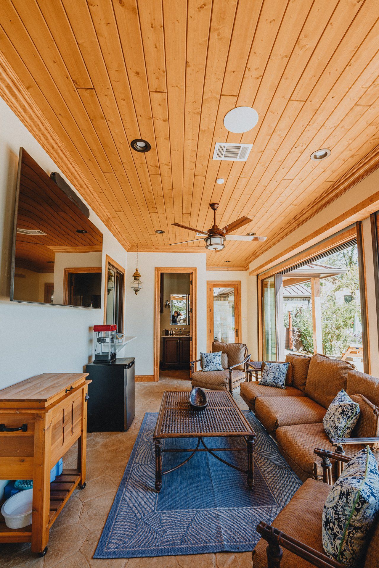 A living room with a wooden ceiling and a ceiling fan.