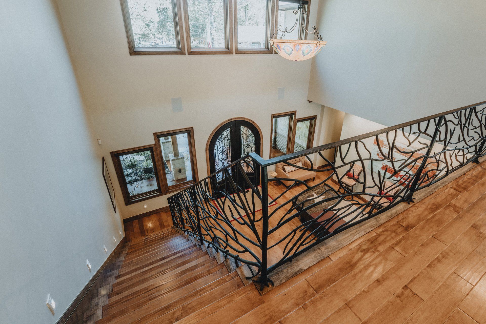 A staircase with a wrought iron railing and wooden floors in a house.