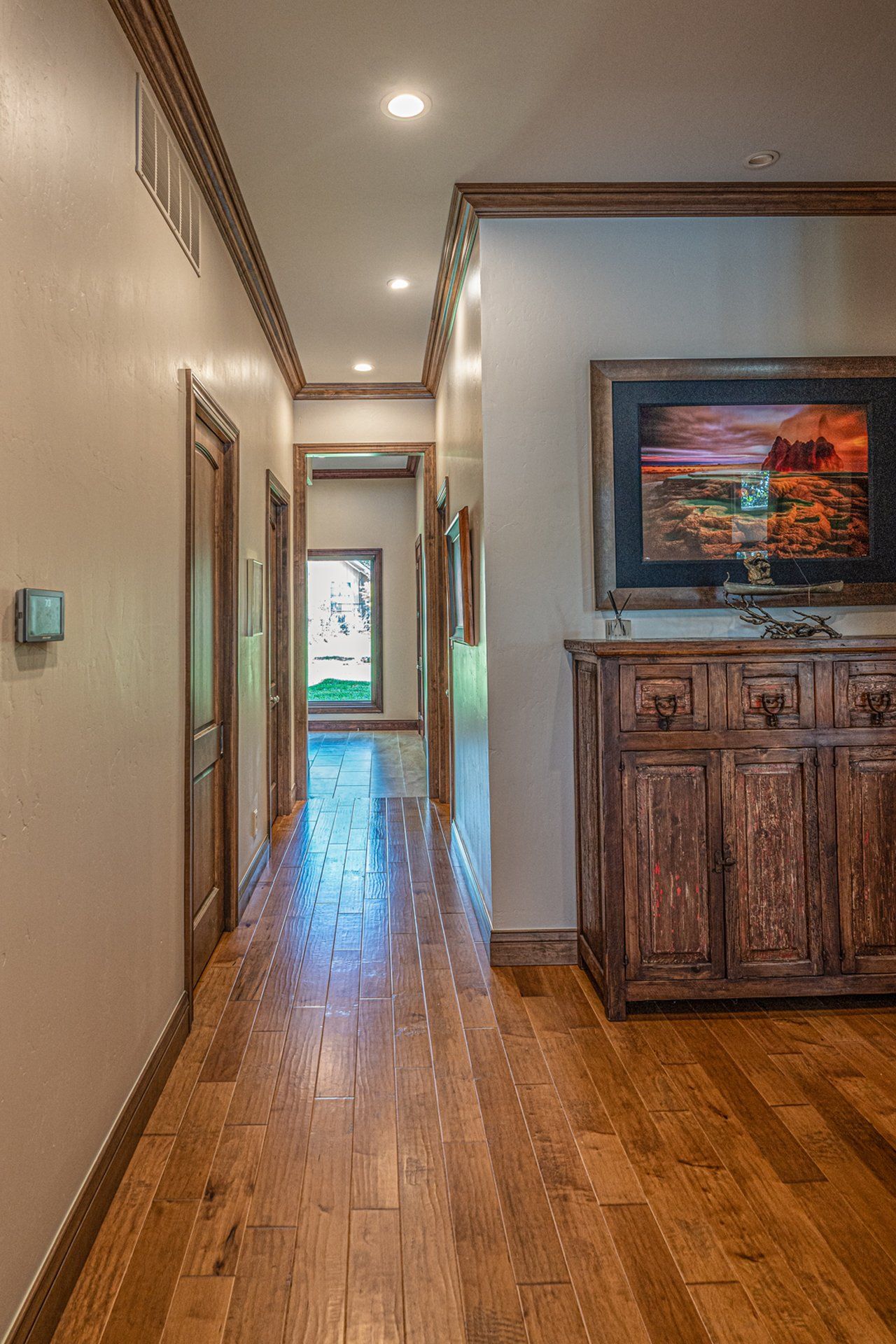A long hallway with hardwood floors and a painting on the wall.