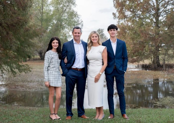 Family of Chasity Verret Martinez posing outdoors near water, wearing formal attire.