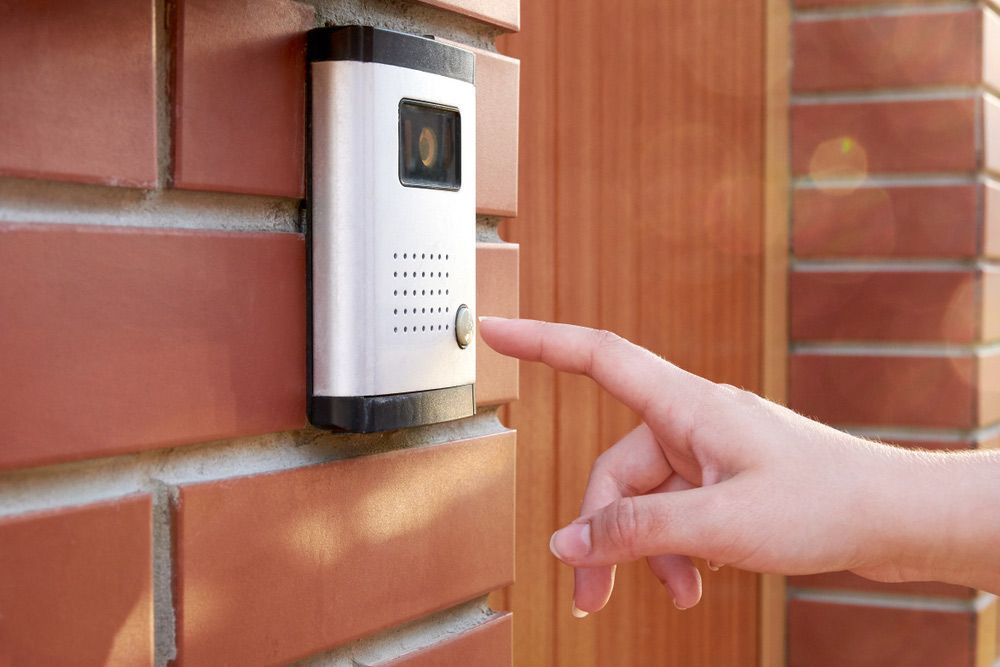 A Person Is Pressing A Doorbell On A Brick Wall — SPL Security Solutions in Bundall, QLD