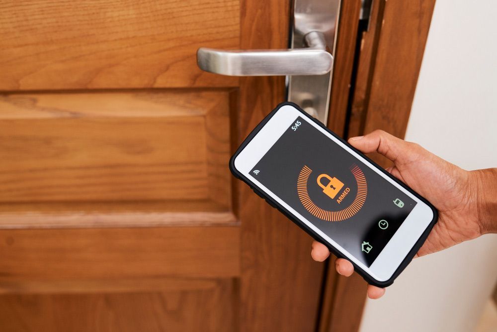 Person Is Holding A Cell Phone In Front Of A Door — SPL Security Solutions in Bundall, QLD
