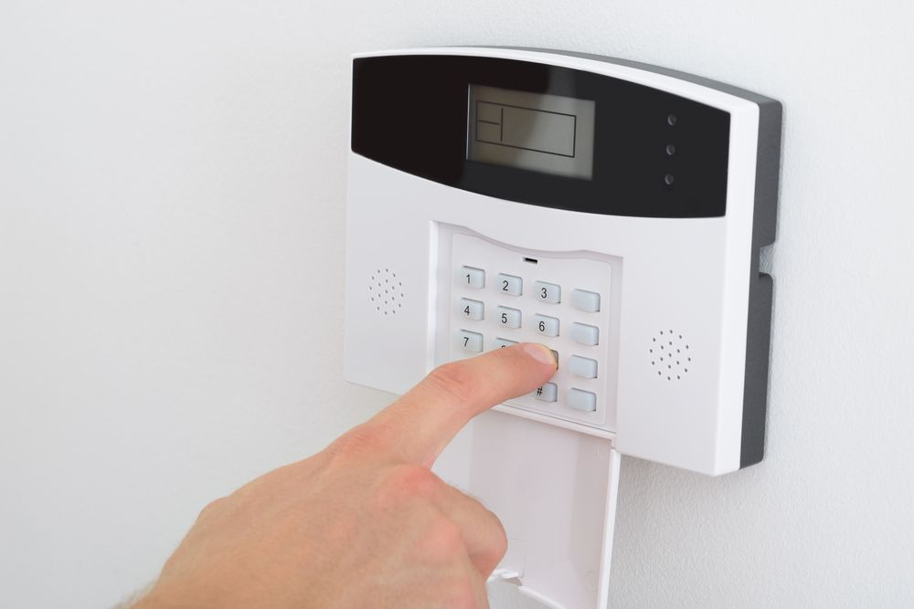 A Person Is Pressing A Button On A Security System — SPL Security Solutions In Palm Beach, QLD