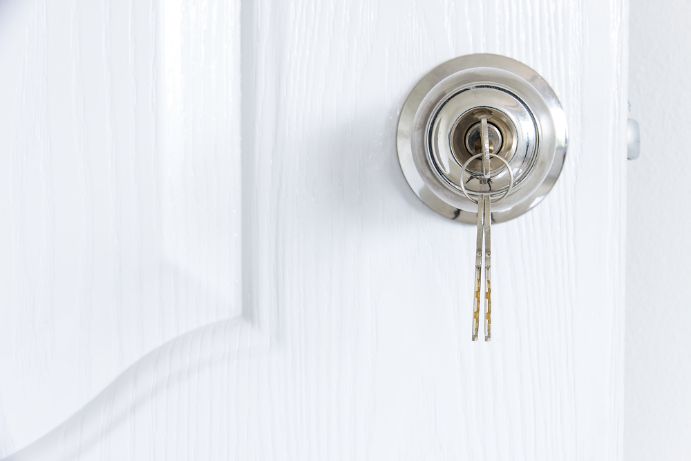 A Close Up Of A Key In A Lock On A White Door — SPL Security Solutions In Runaway Bay, QLD