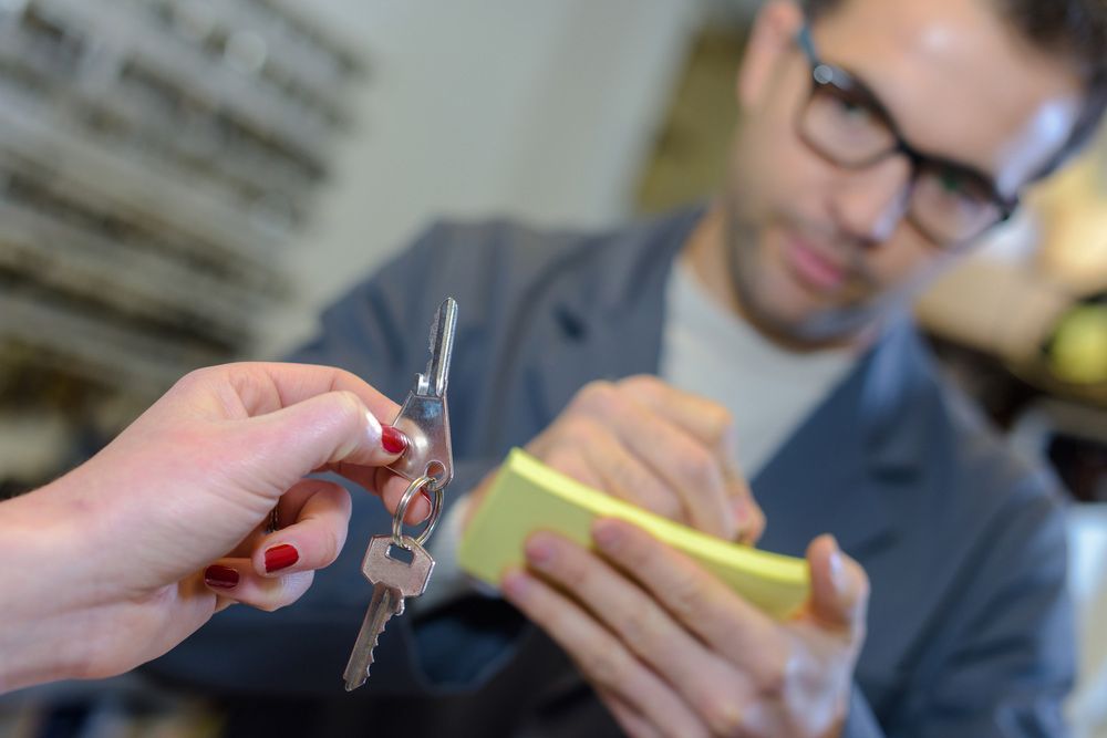 A Man Is Holding A Sticky Note And A Woman Is Holding A Pair Of Keys — SPL Security Solutions In Yatala, QLD