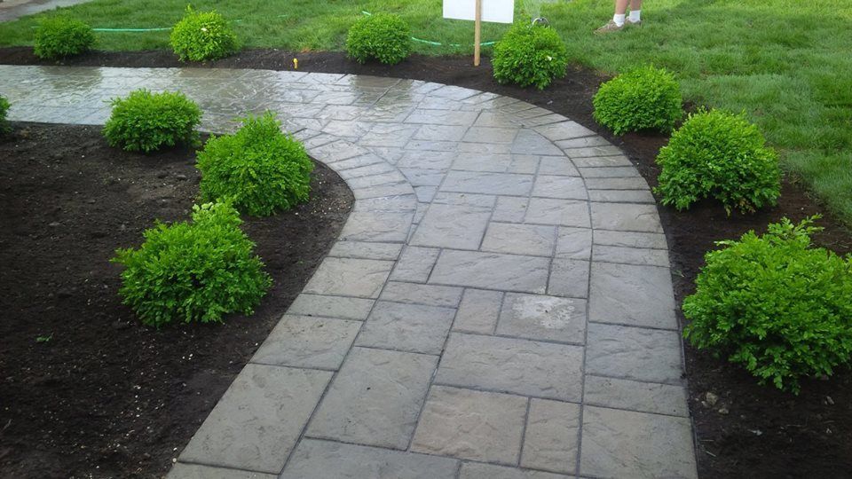 grey unistone walkway surrounded by green bushes