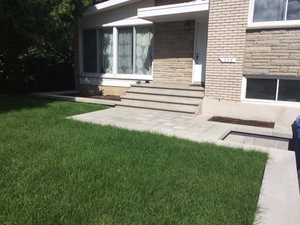 front yard with green grass and beige unistone walkway and stairs