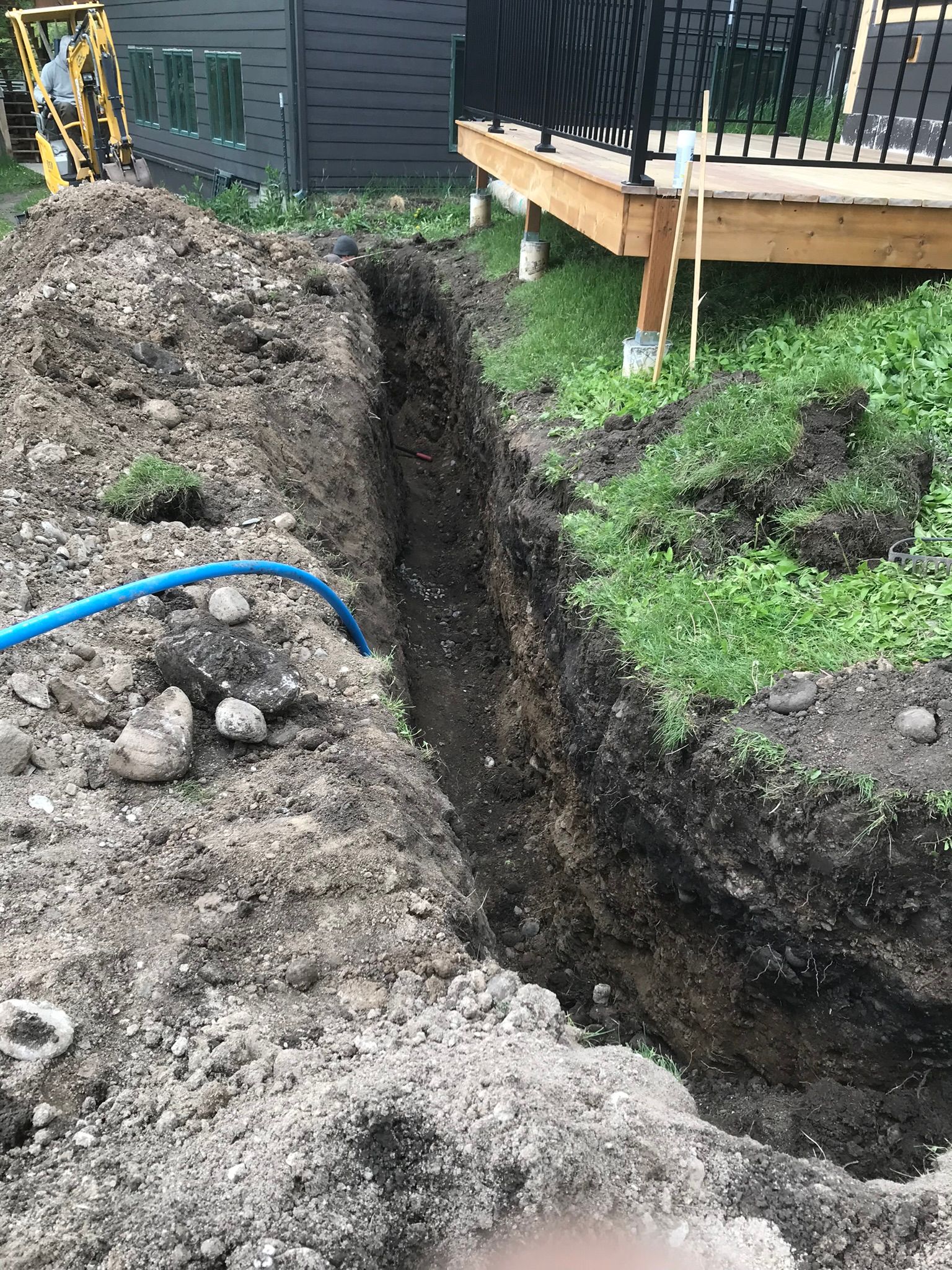 A person is digging a hole in the ground in front of a house.