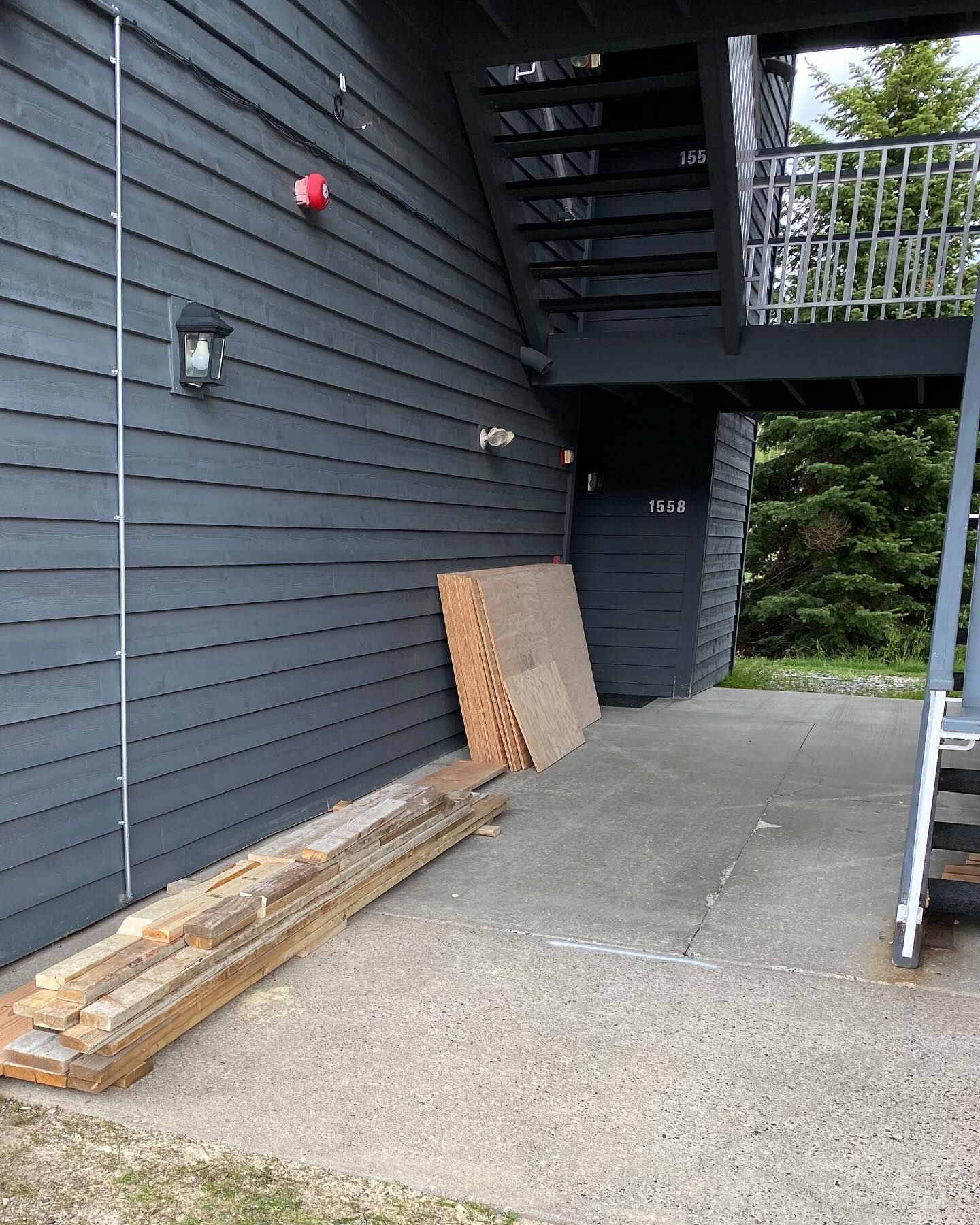A stack of wood sits on the side of a building next to stairs