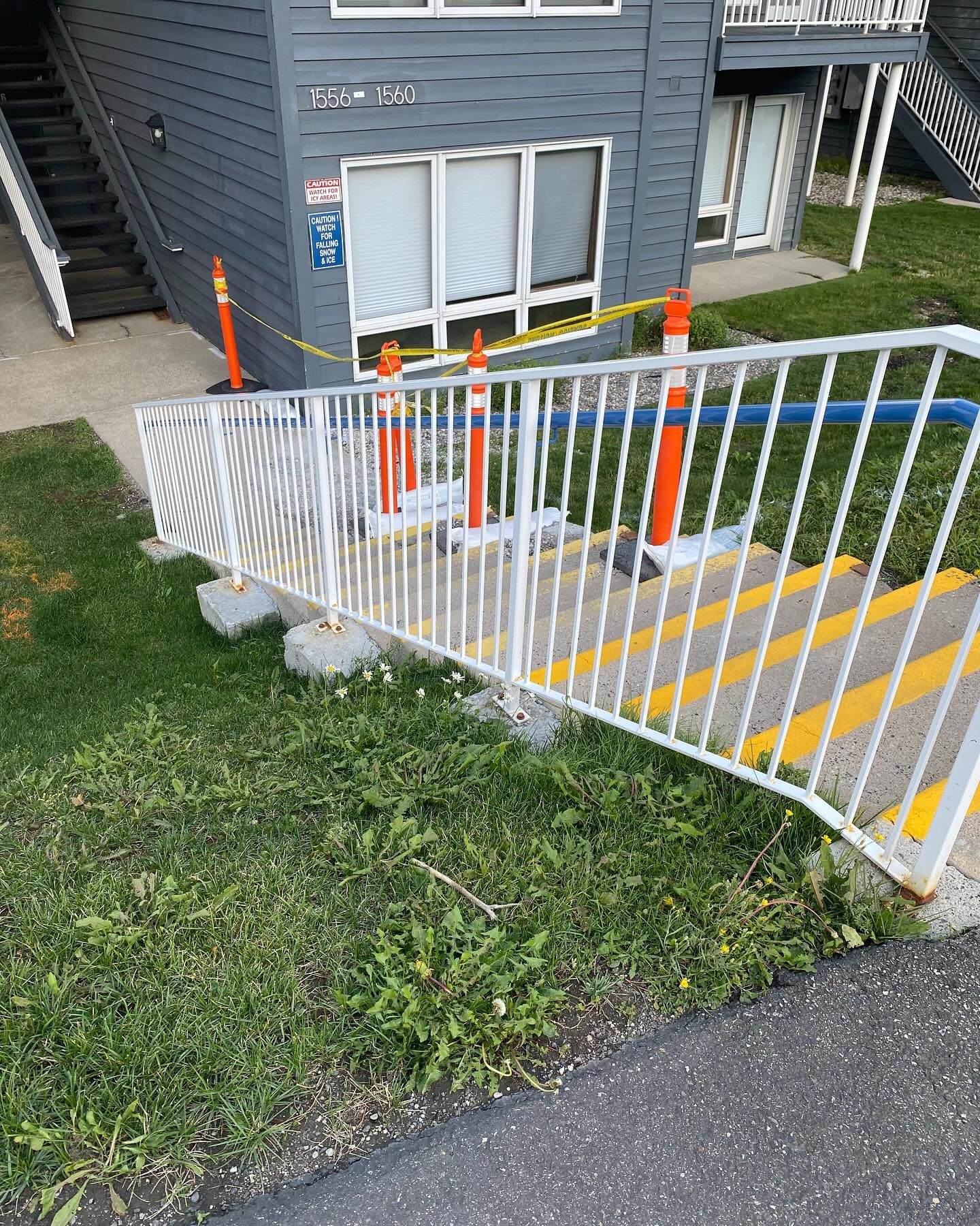 A broken railing is blocking the stairs to a building.