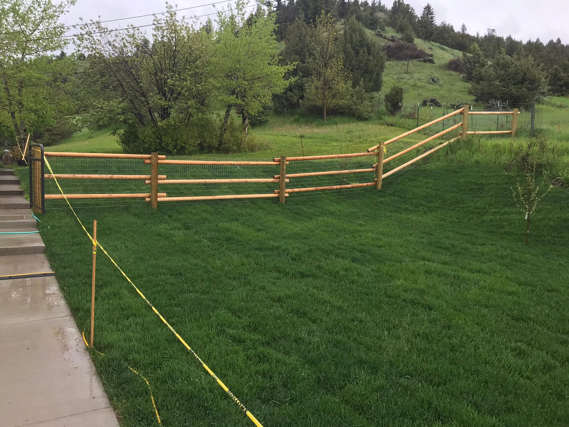 A wooden fence surrounds a lush green field.