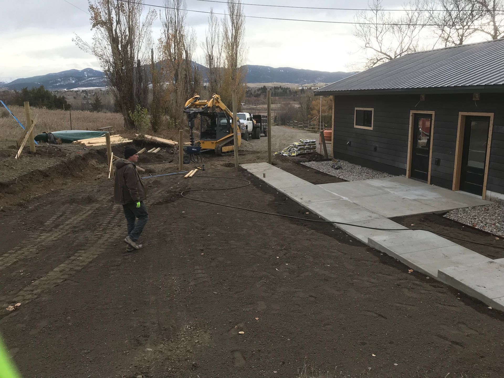 A man is standing in a dirt field in front of a house.