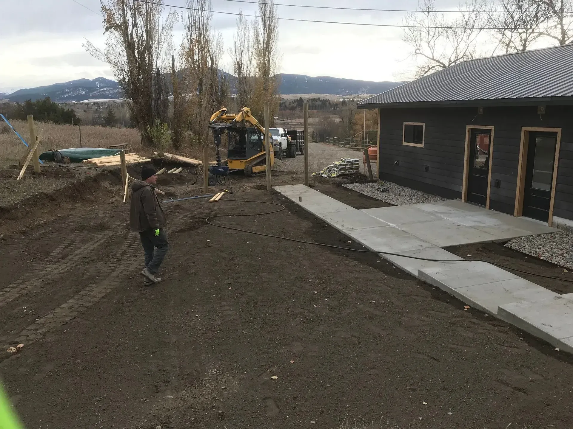 A man is standing in a dirt field in front of a building.