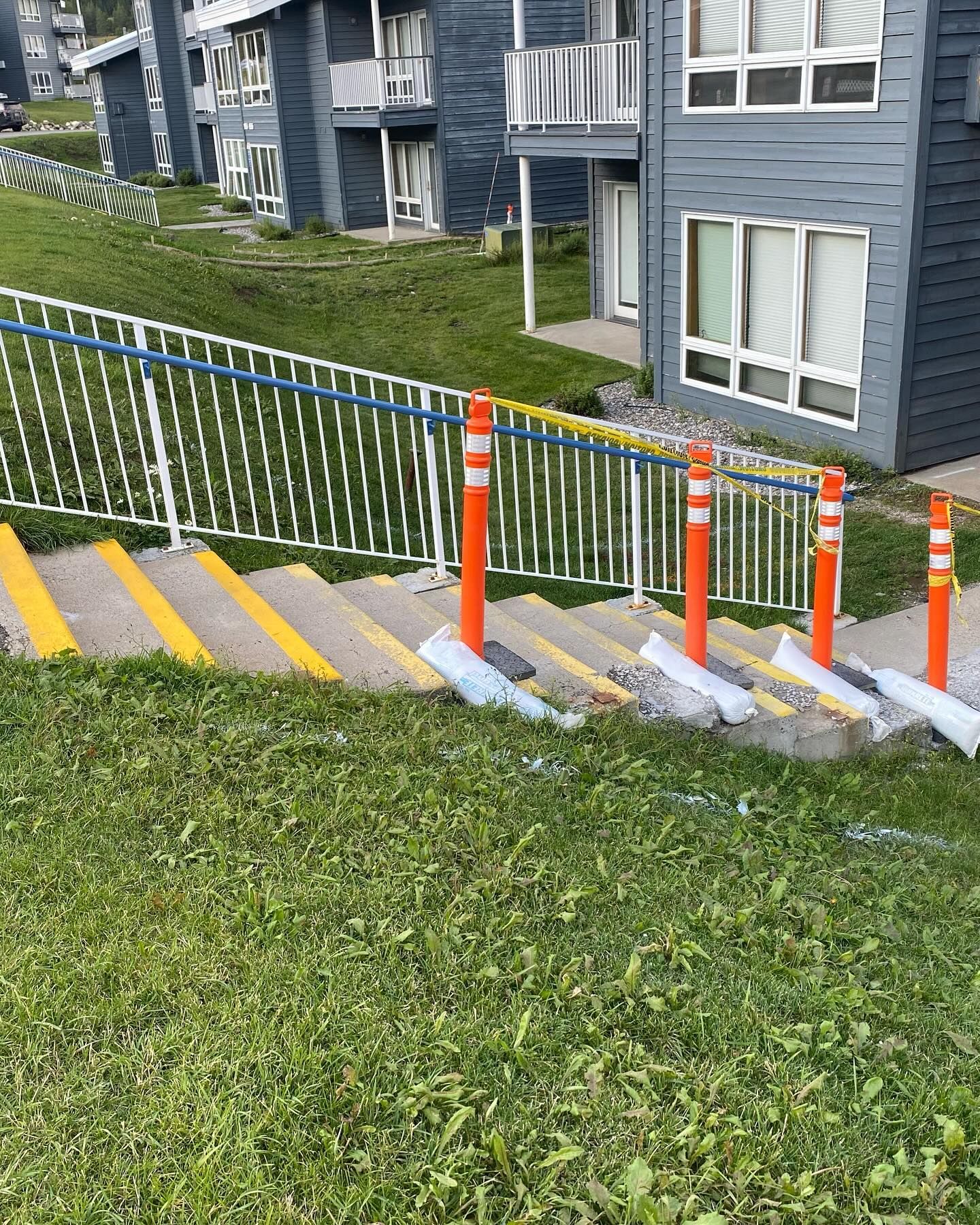 A set of stairs leading up to a building with a fence and orange poles.