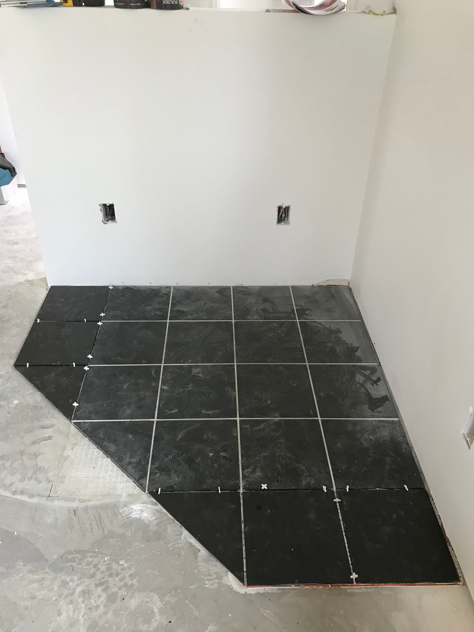 A black tile floor is being installed in a room.