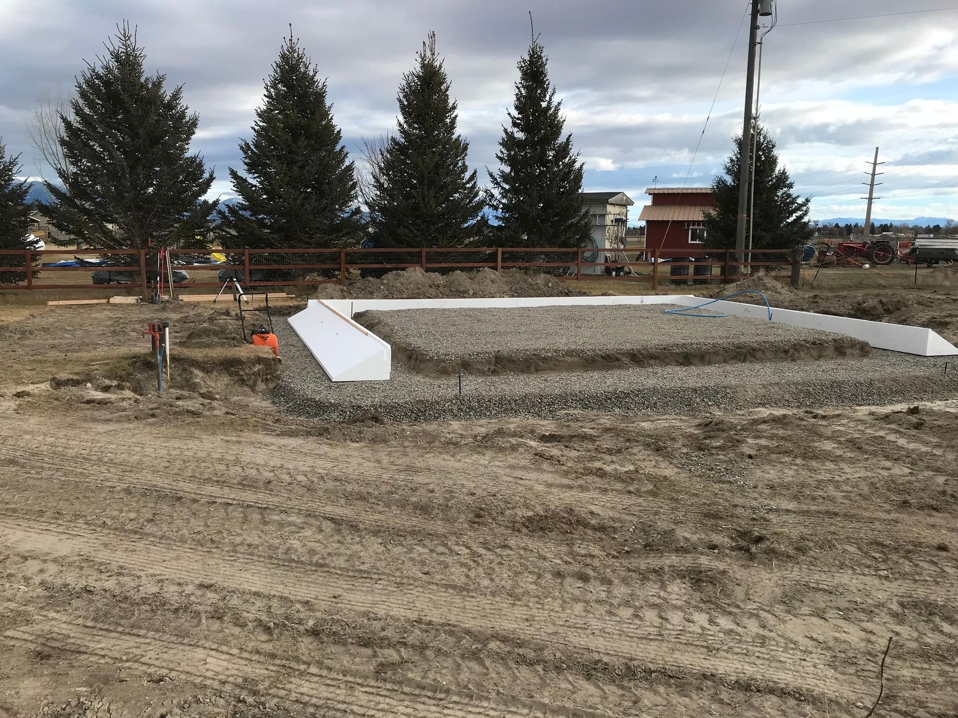 A dirt field with a fence and trees in the background.