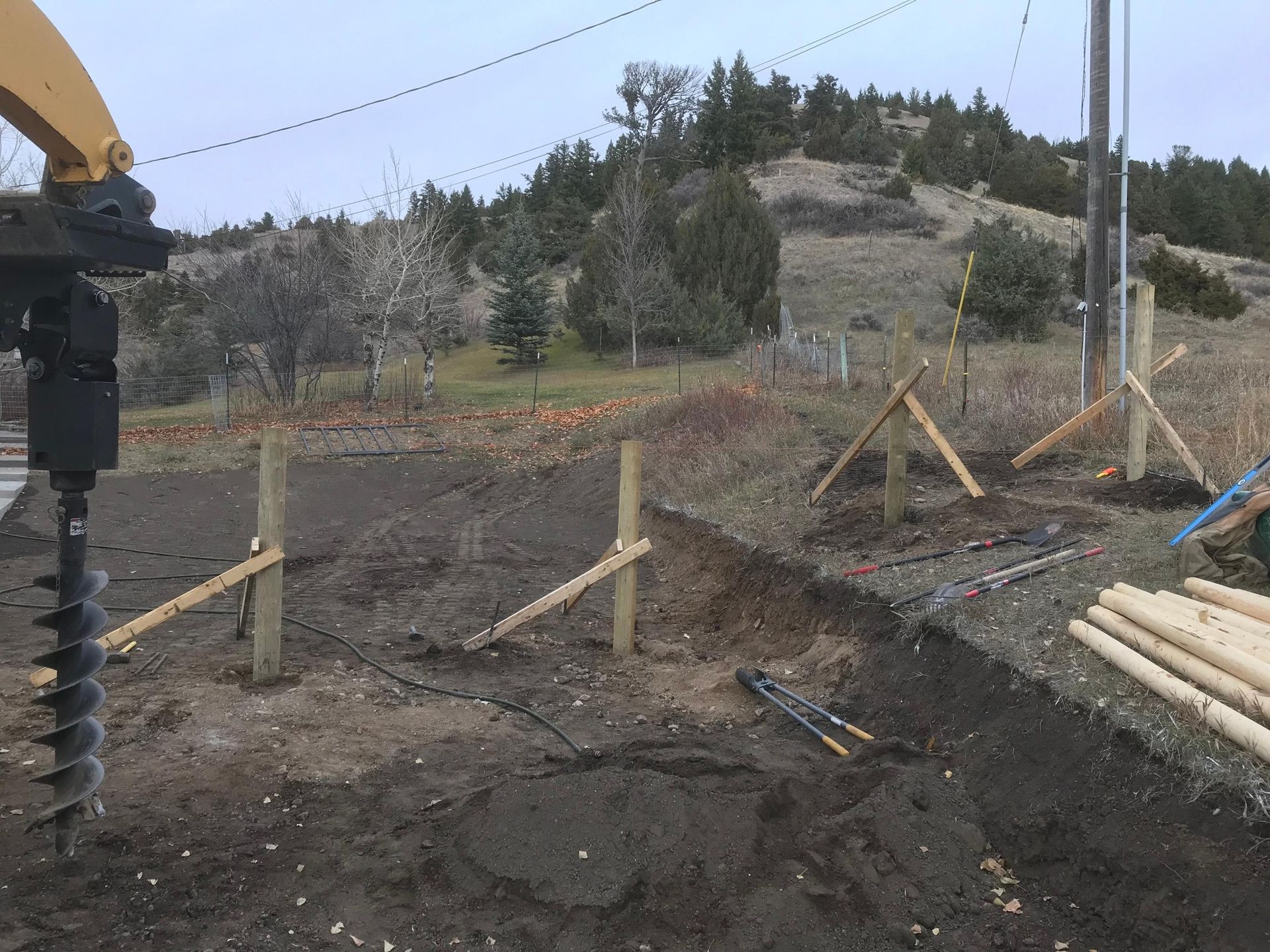 A fence is being built in a dirt field.