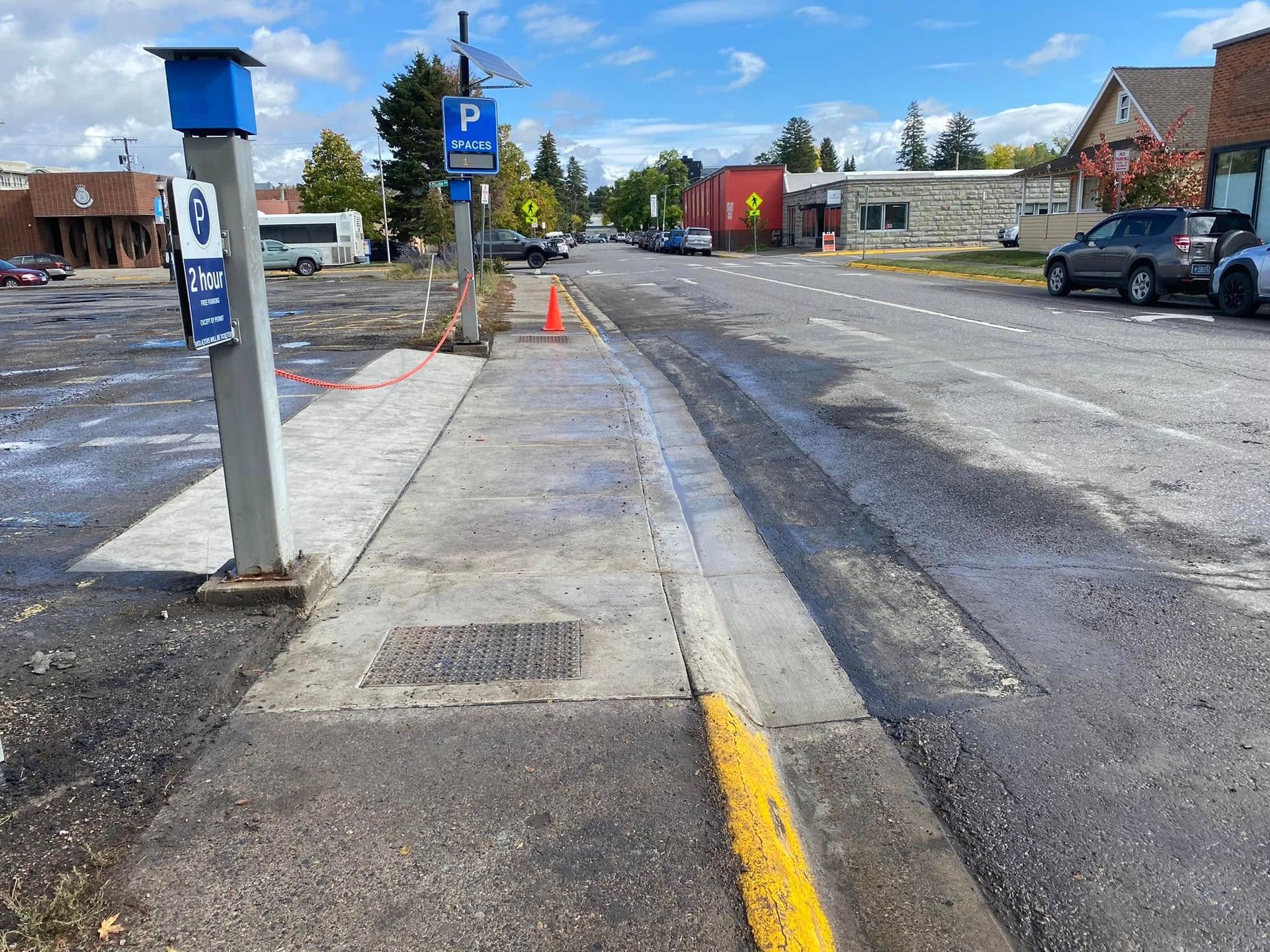A parking meter is sitting on the side of the road next to a sidewalk.