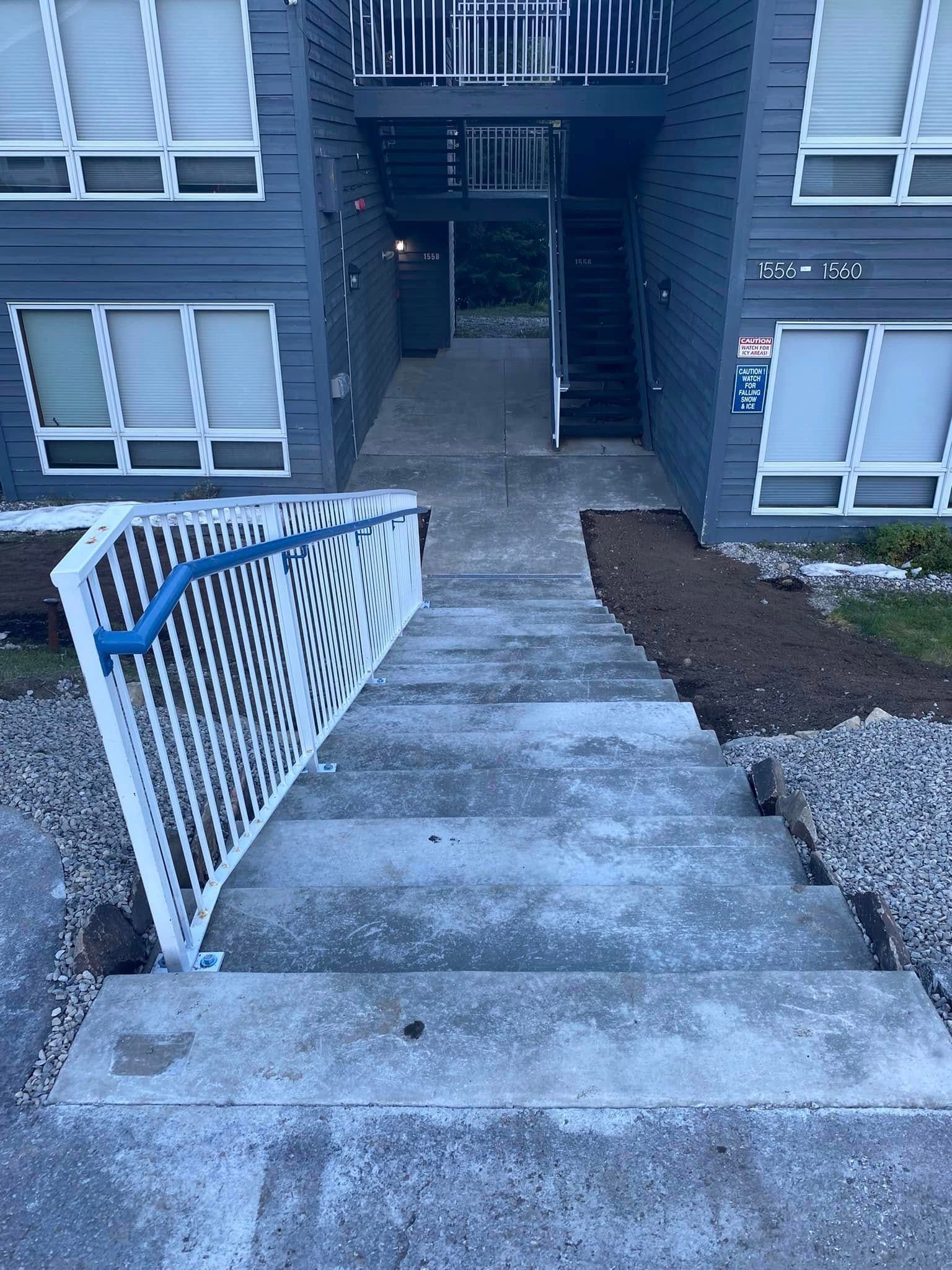 A set of stairs leading up to a building with a blue railing.