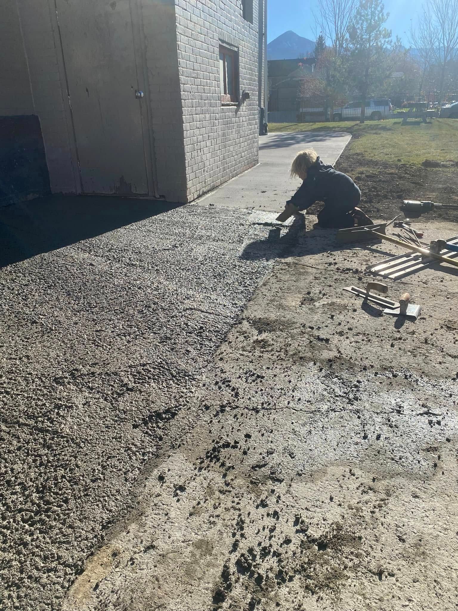 A man is kneeling in the dirt in front of a building.