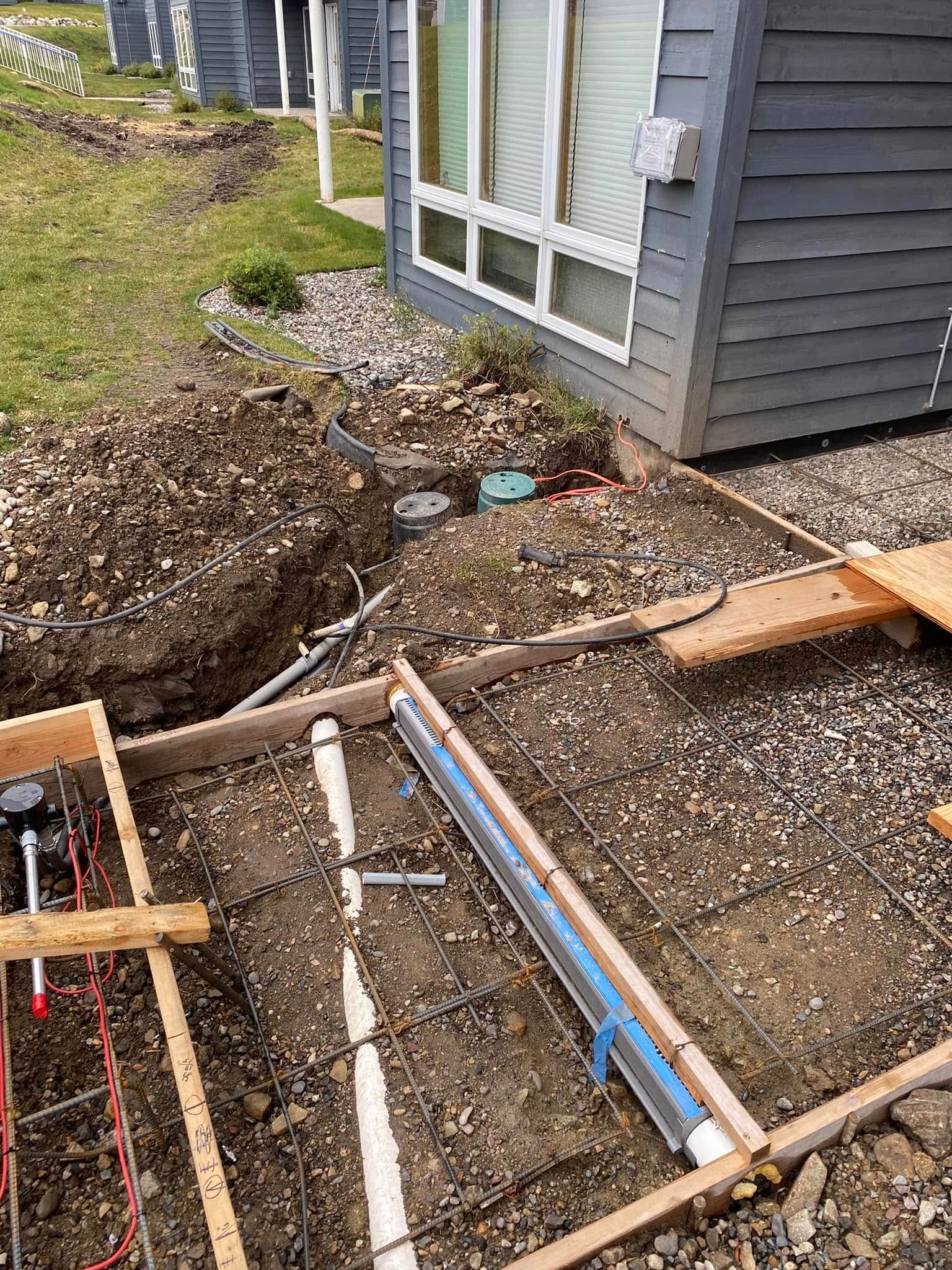 A house with a lot of pipes in the ground in front of it.