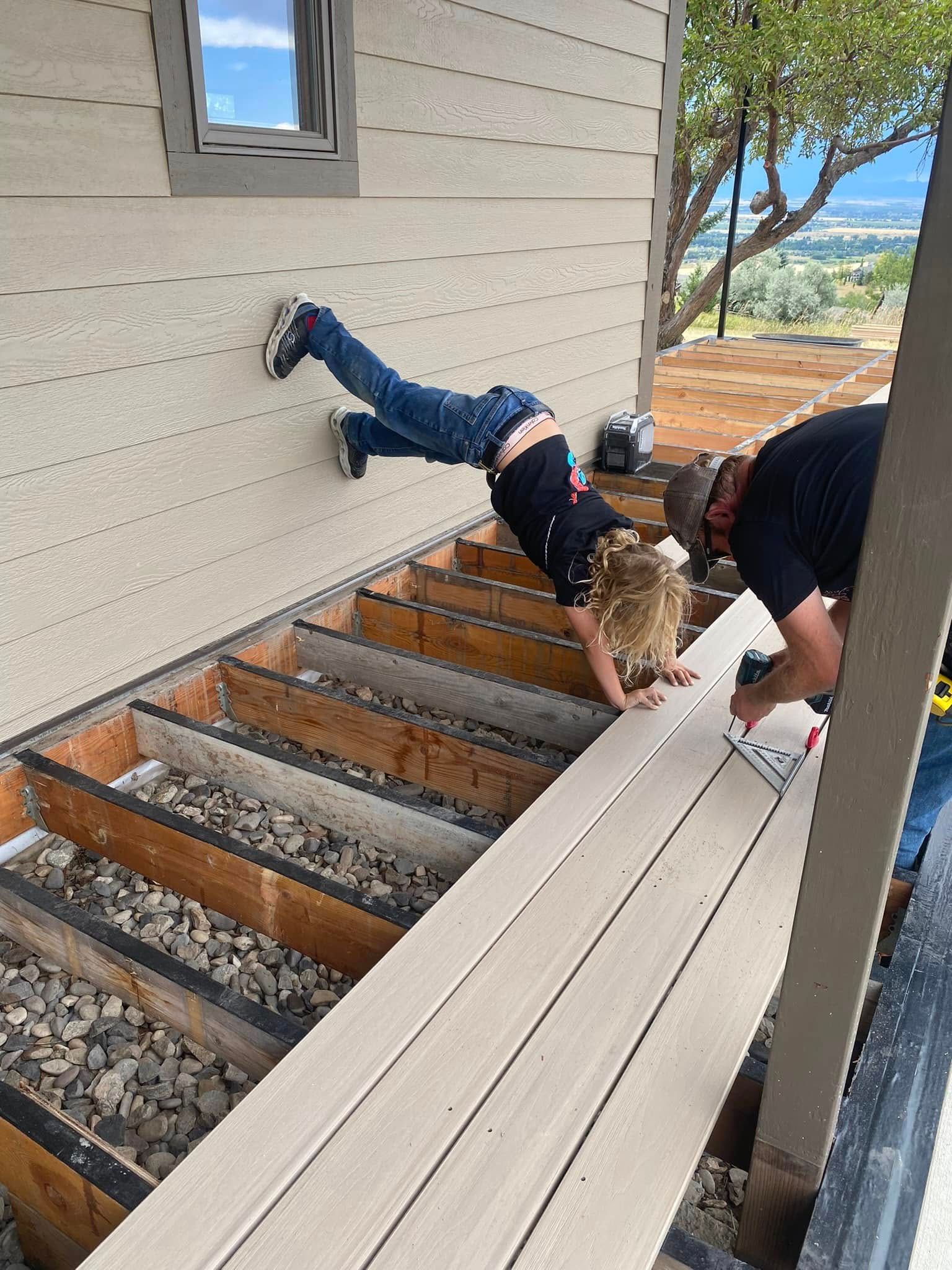 A boy is doing a handstand on a deck under construction.