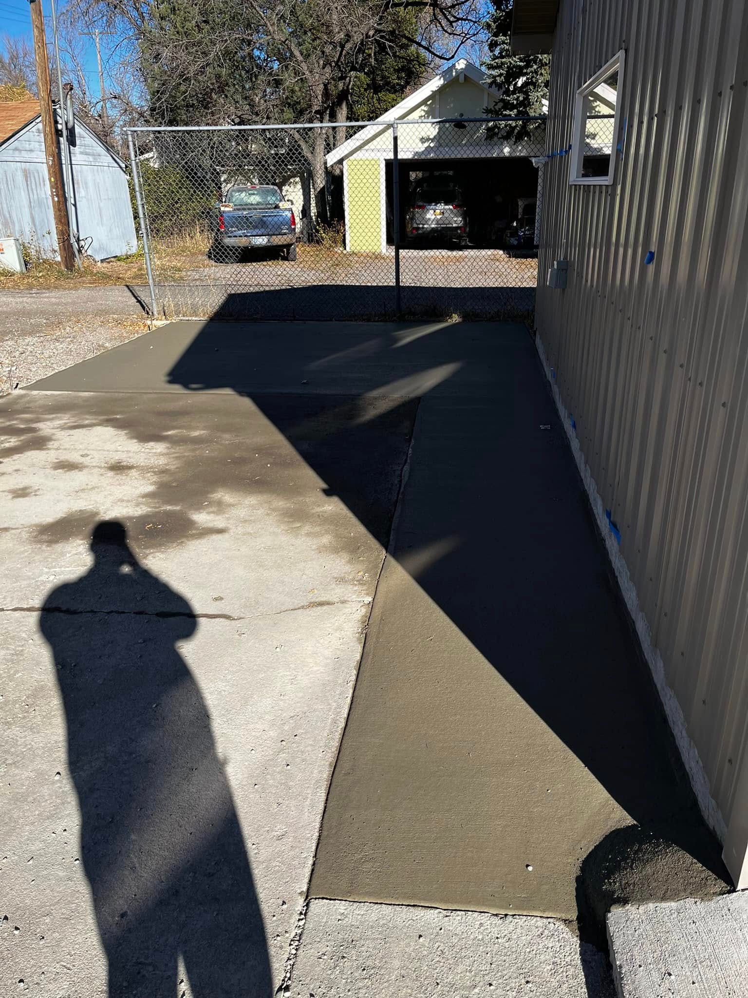 A shadow of a person is cast on the sidewalk in front of a house.