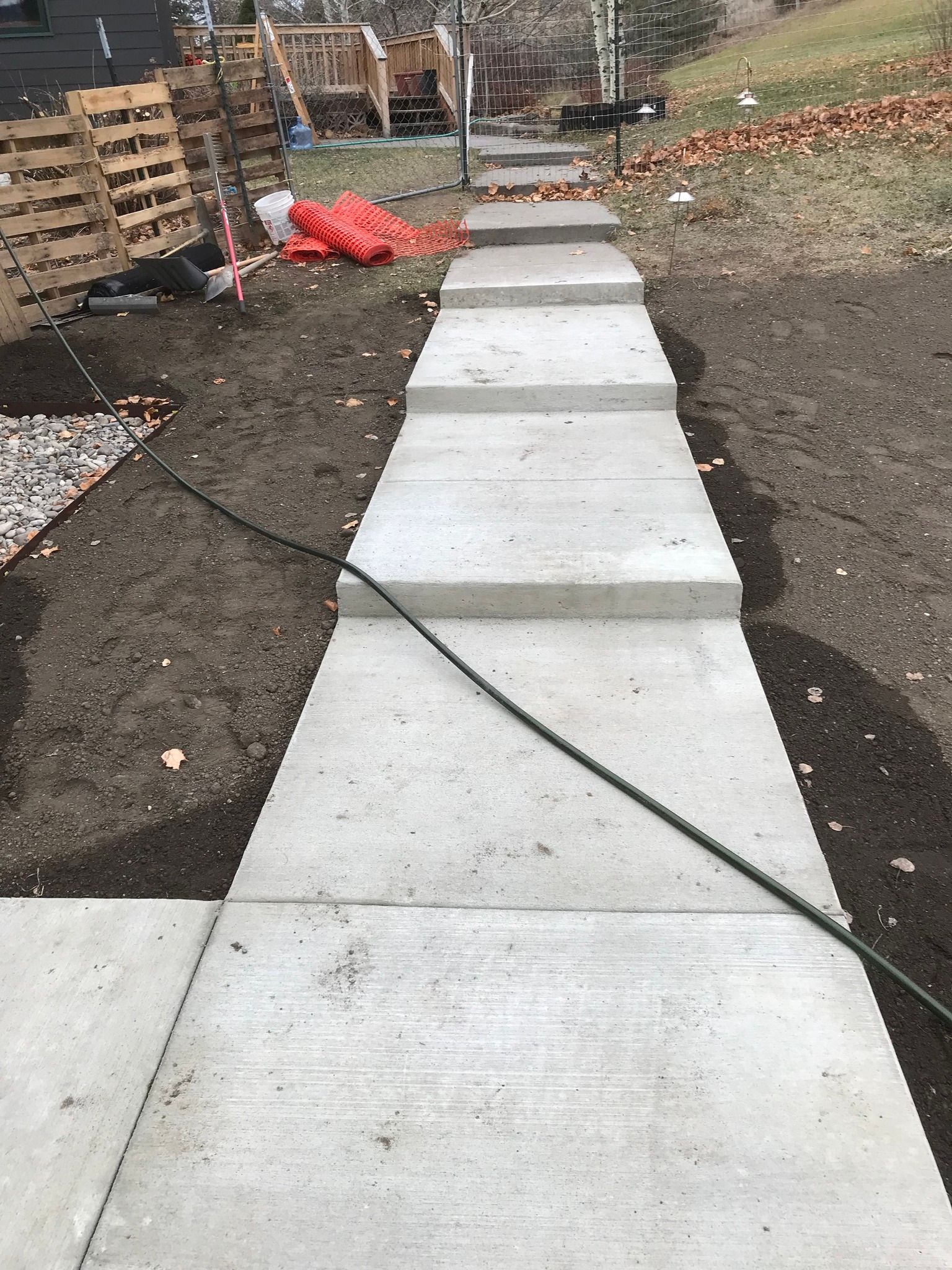 A concrete walkway is being built in a backyard.
