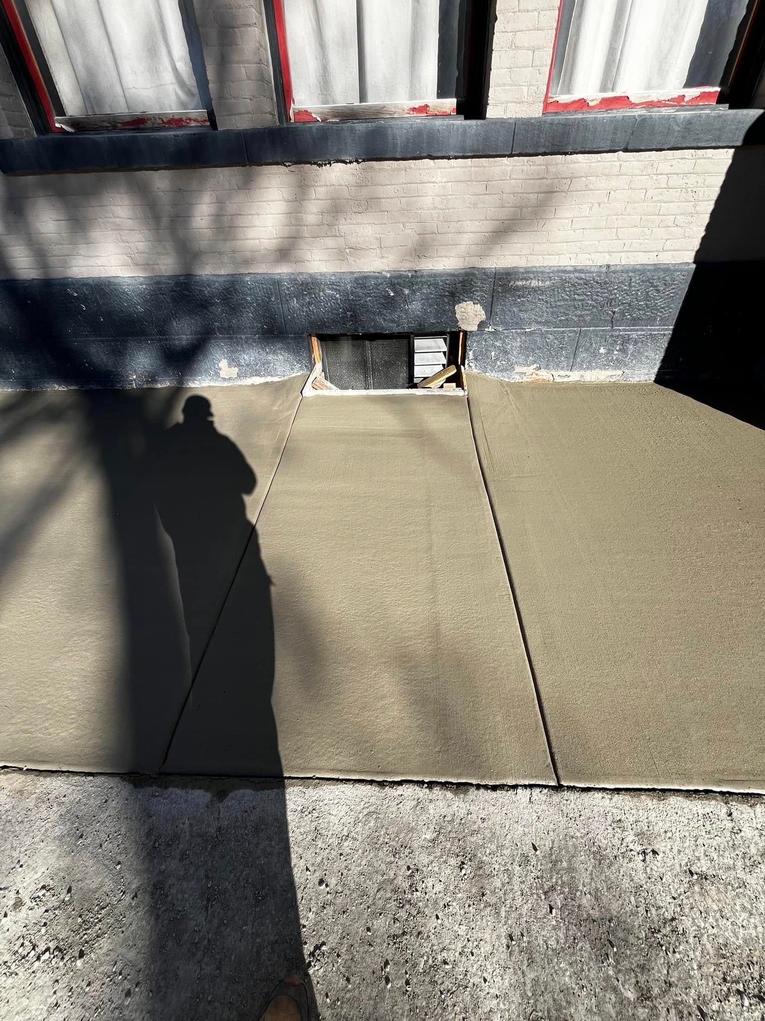 A shadow of a person is cast on a concrete surface.