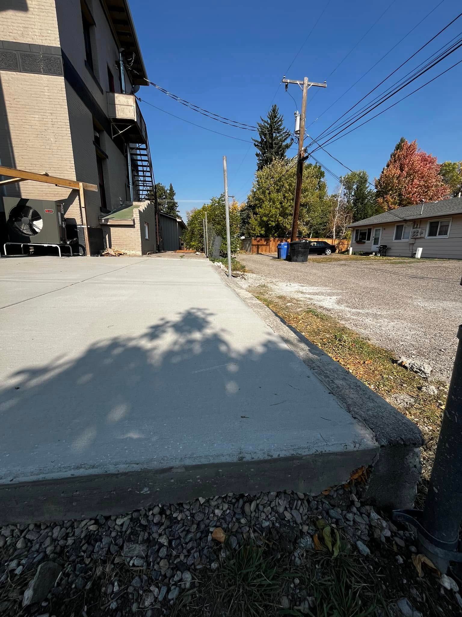 A sidewalk with a shadow of a tree on it in front of a building.
