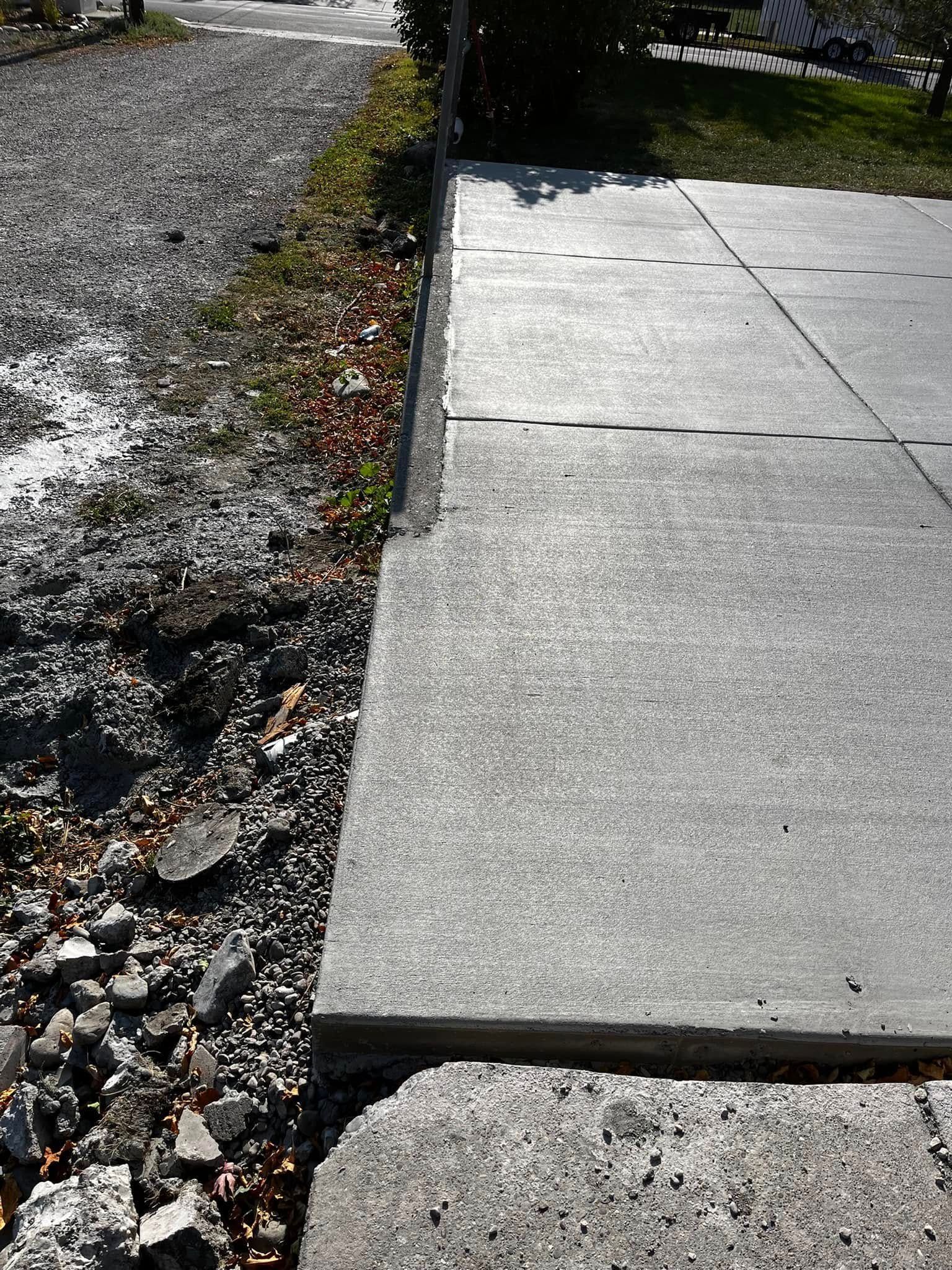 A concrete sidewalk is sitting next to a gravel road.
