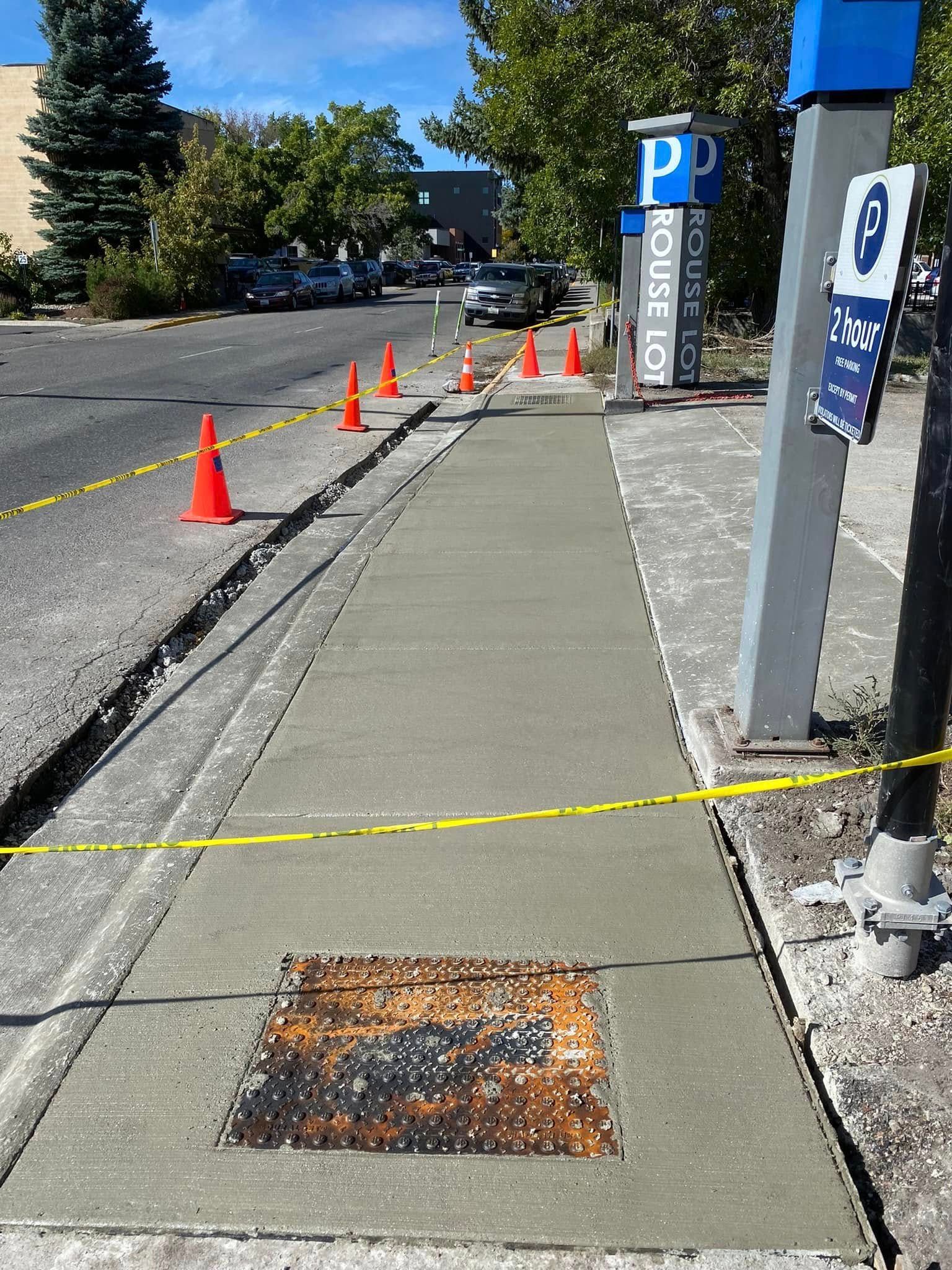 A sidewalk is being built next to a parking lot.