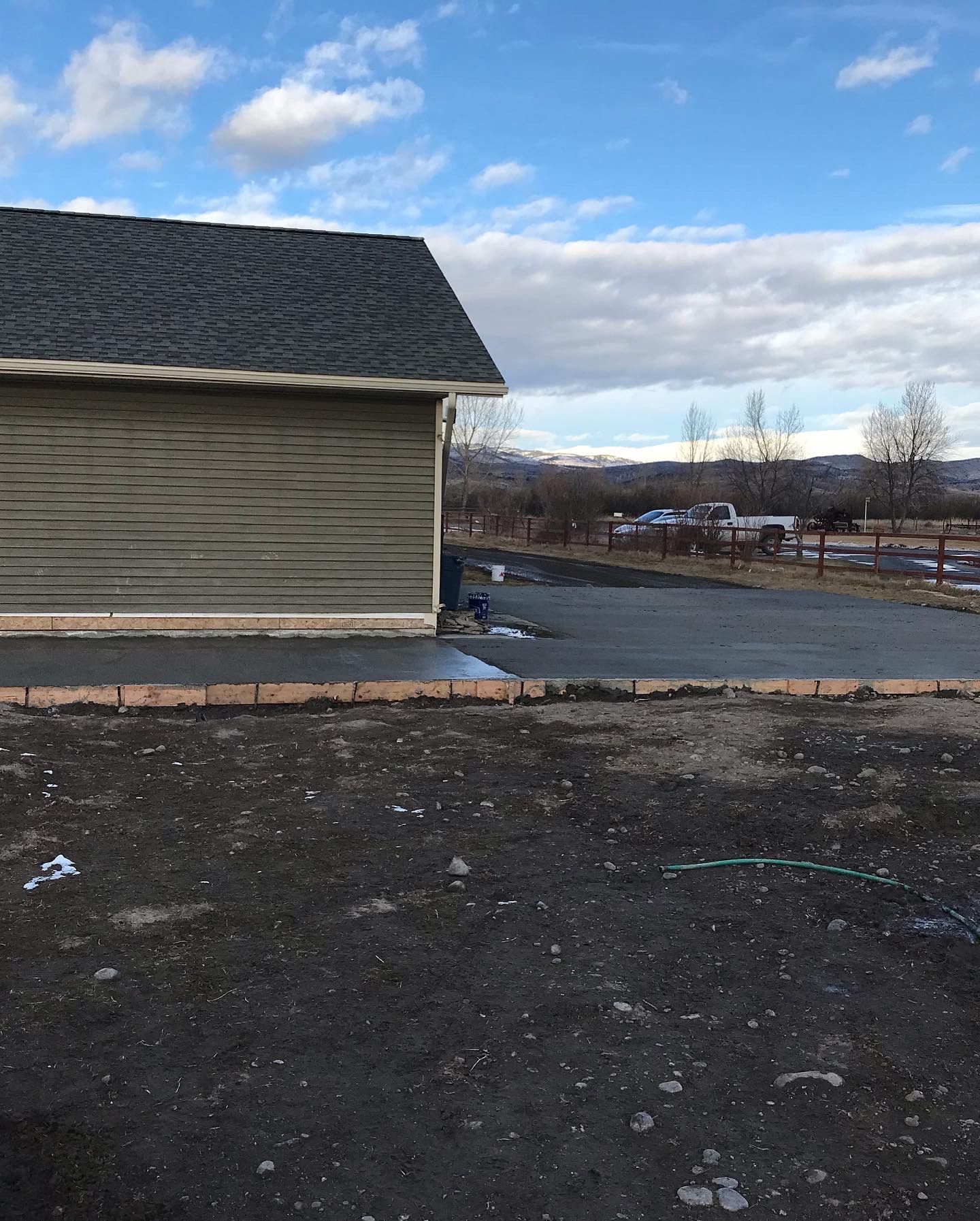 A house with a gray roof is sitting in the middle of a dirt field.