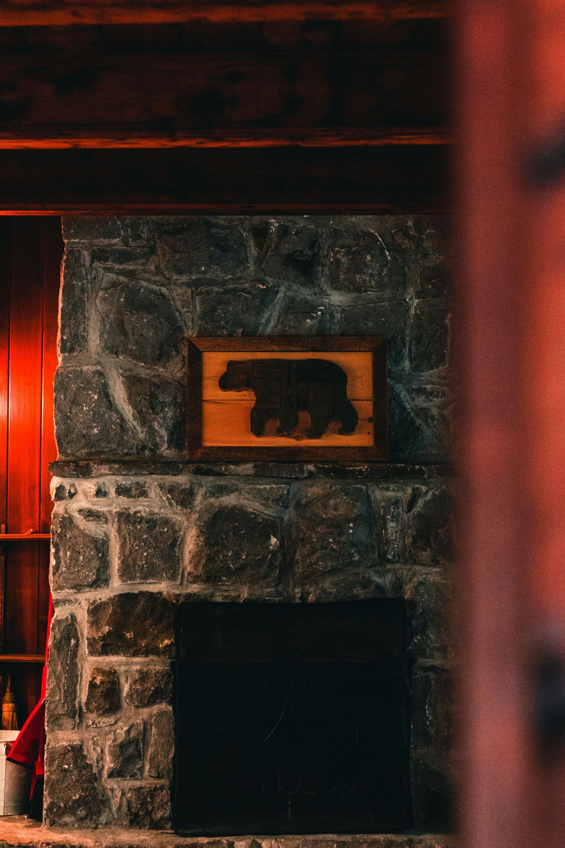 Stone fireplace with a framed bear silhouette; inside a rustic cabin.