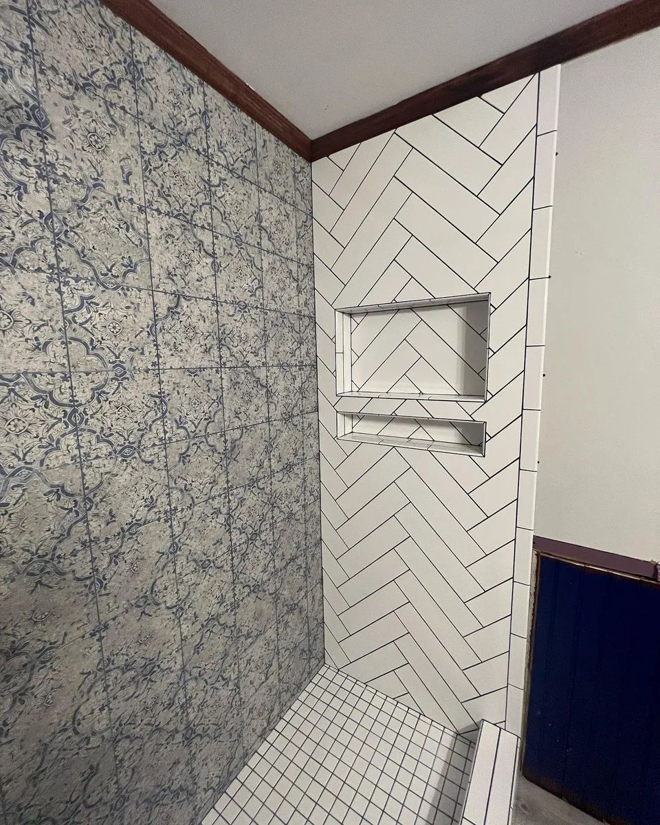Shower with patterned blue and white tile, herringbone pattern in shower niche, and wooden trim.